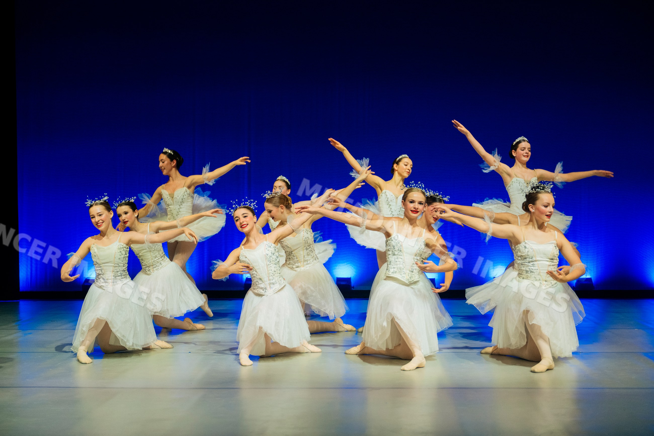 Ballet dancers perform an elegant group dance in white tutus on stage
