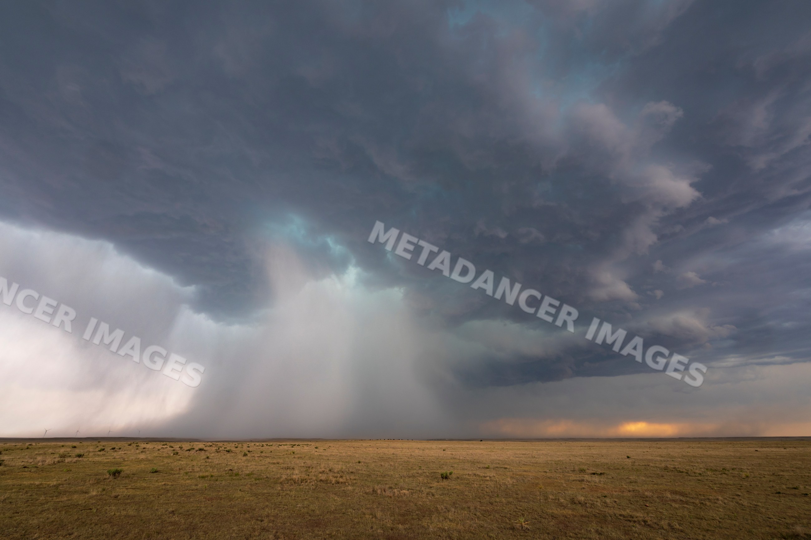 Storm clouds unleashing heavy rain over dry grassland prairie