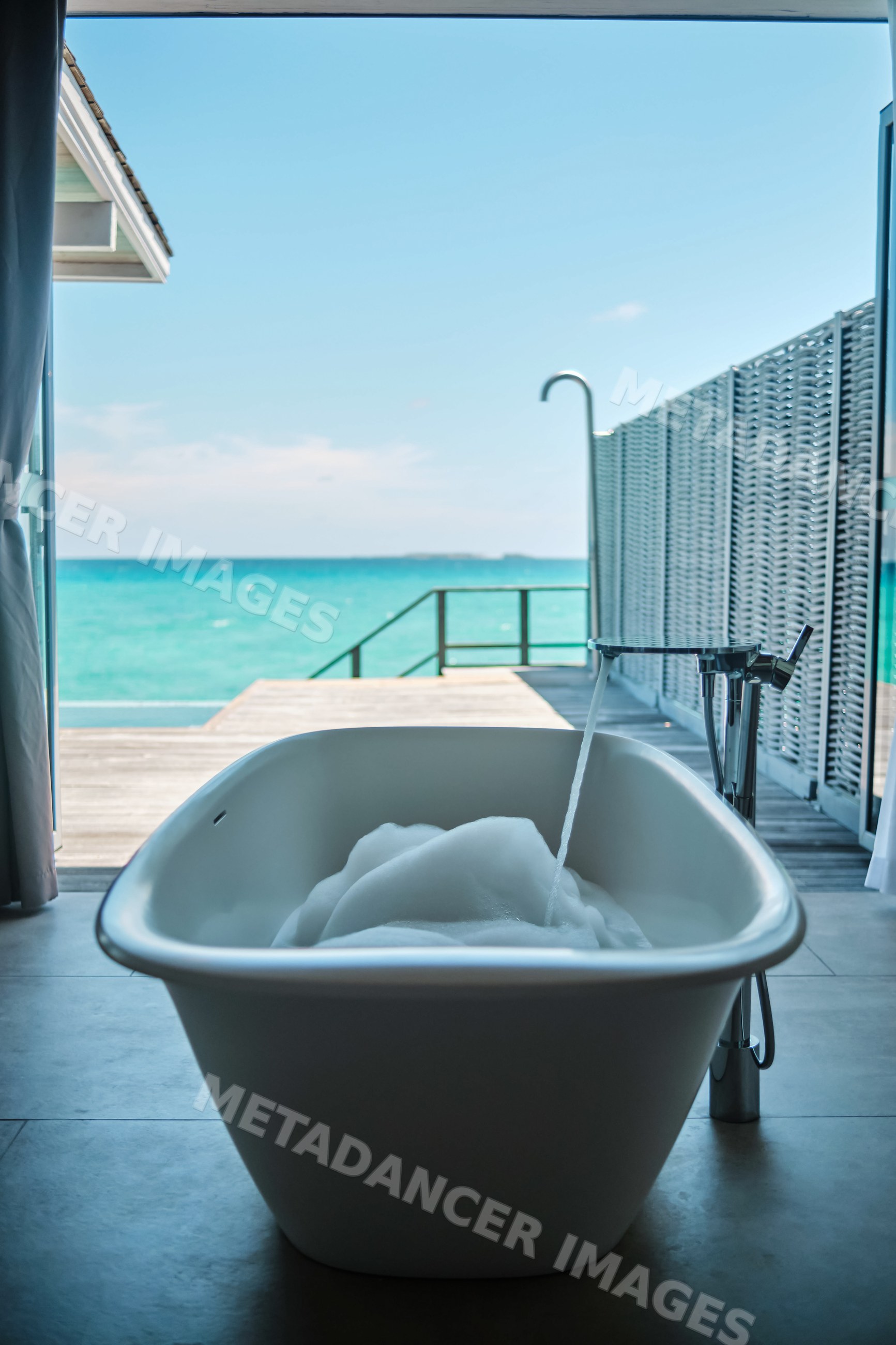 A freestanding bathtub with bubbles overlooking the ocean