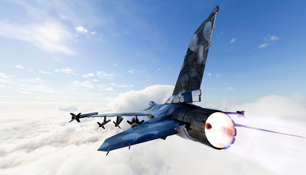 A military fighter jet flies above the clouds with afterburner