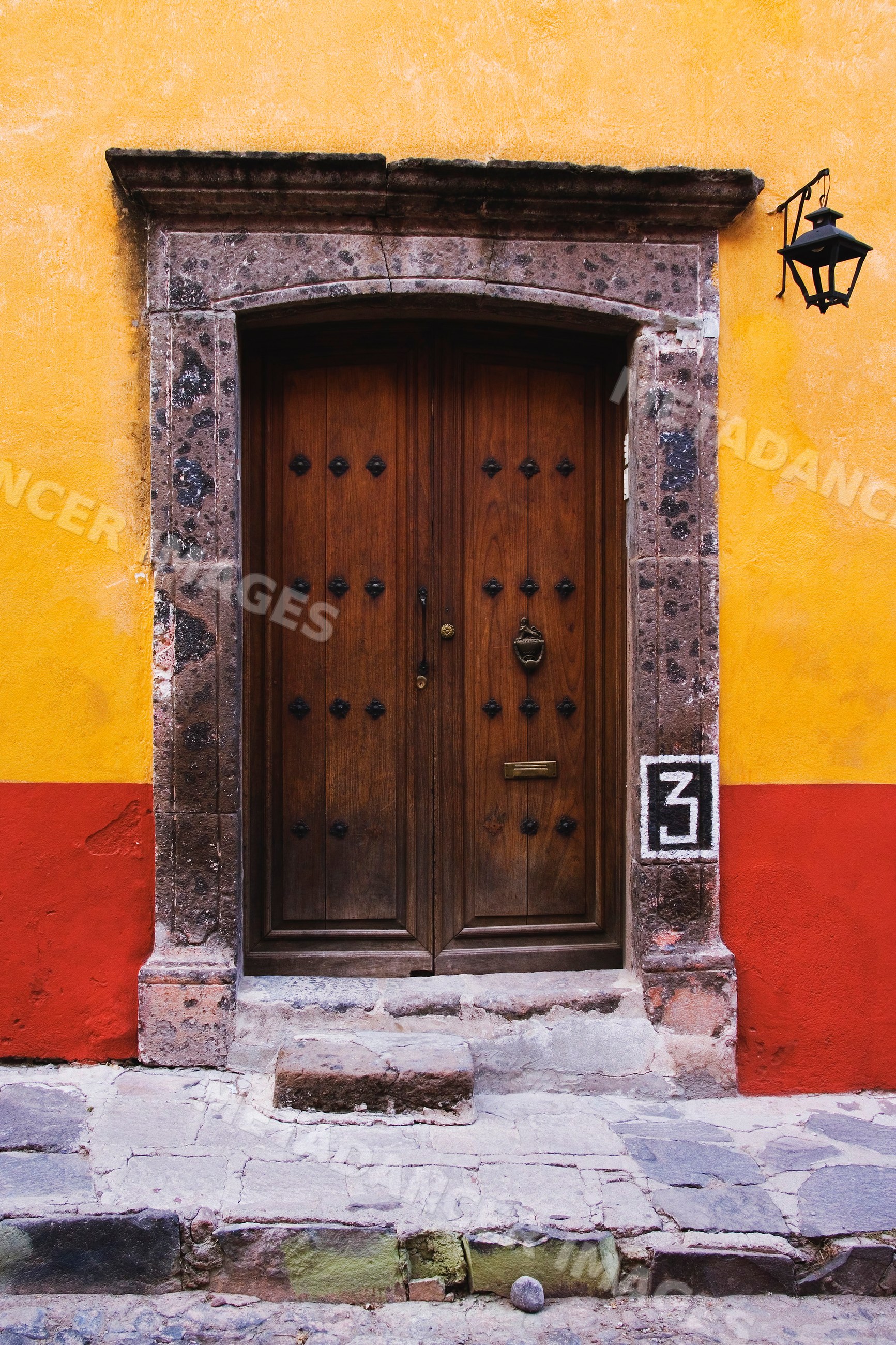 Wooden door framed by stone doorway on colorful wall, mexico