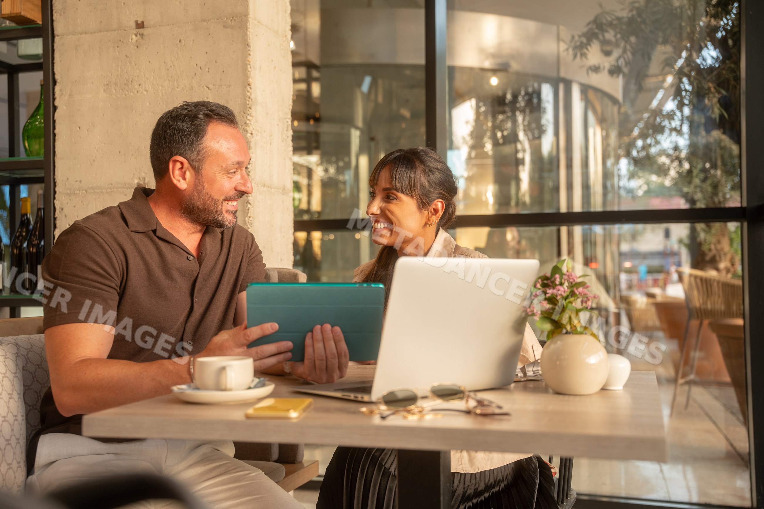 Coworkers having business discussion with laptop and tablet at cafe