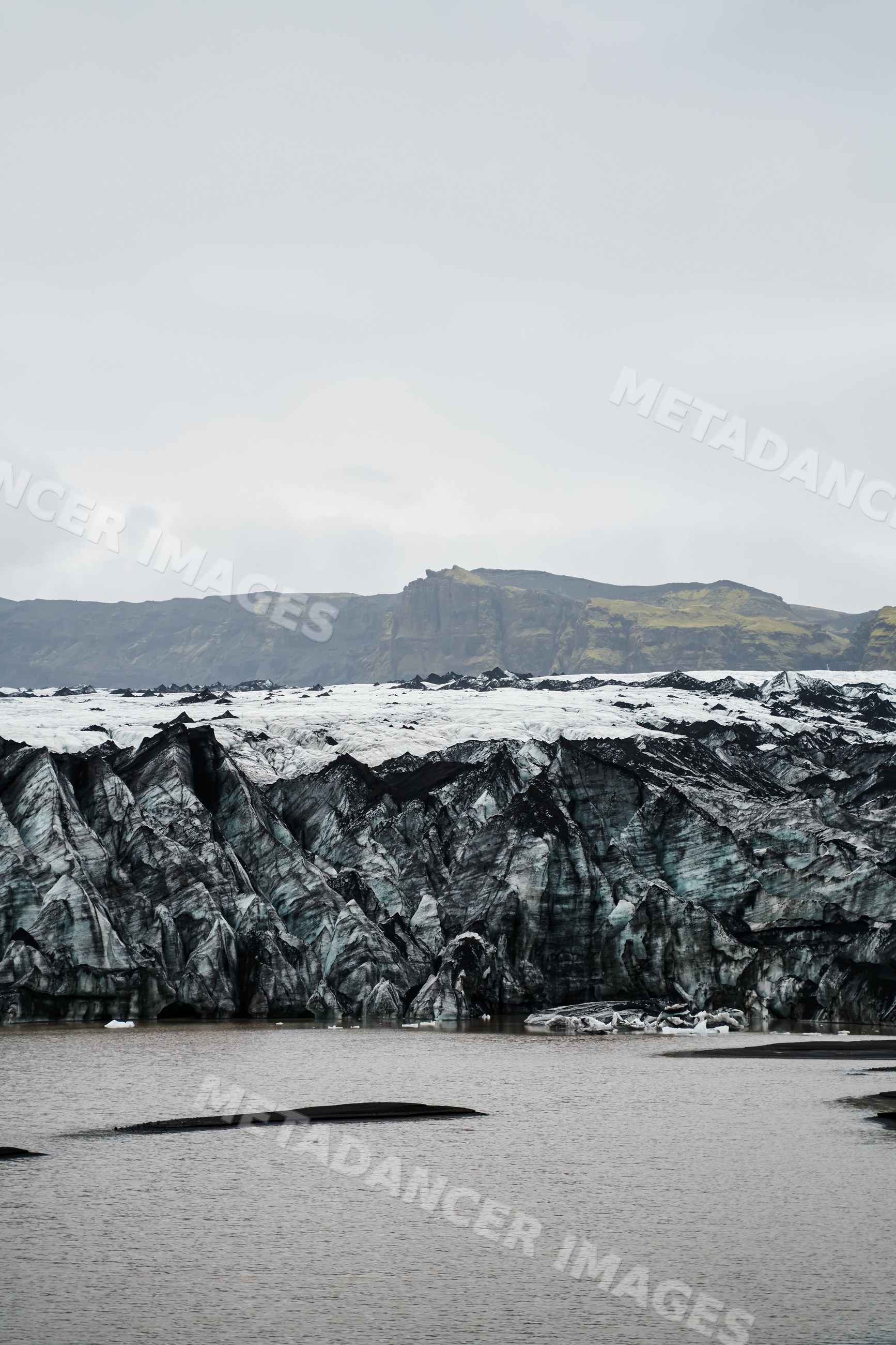 Glacier and lake with icebergs alongside rocky cliffs