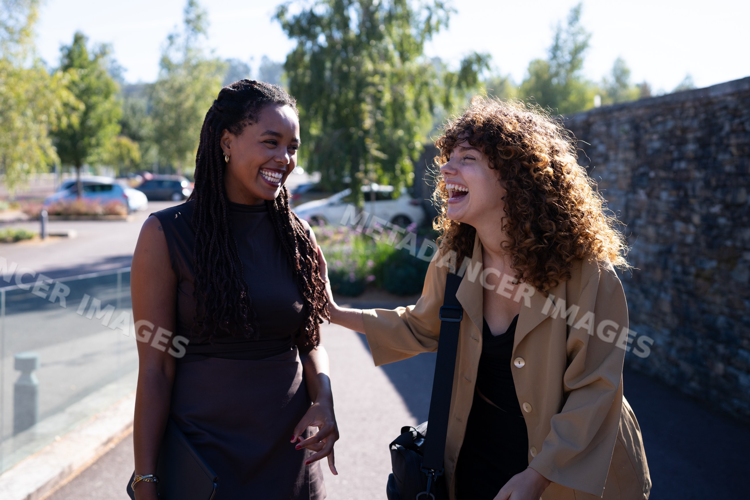 Two African American and white women laughing together outdoors
