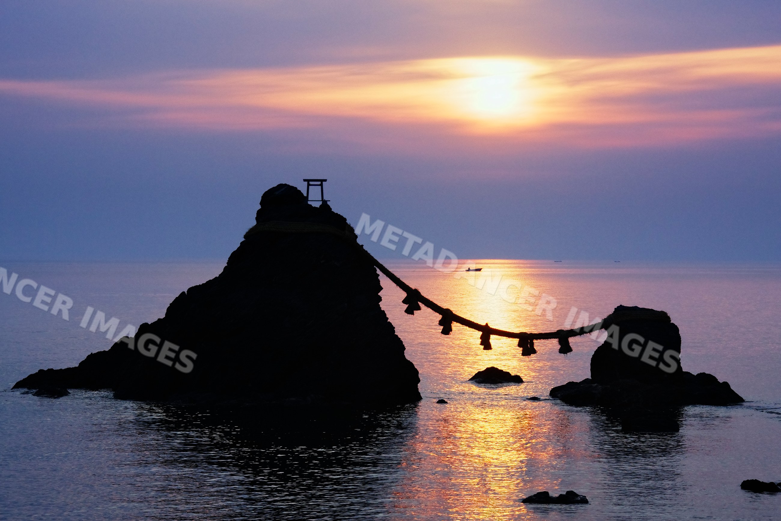 Sunset over meoto iwa rock formation and torii japan