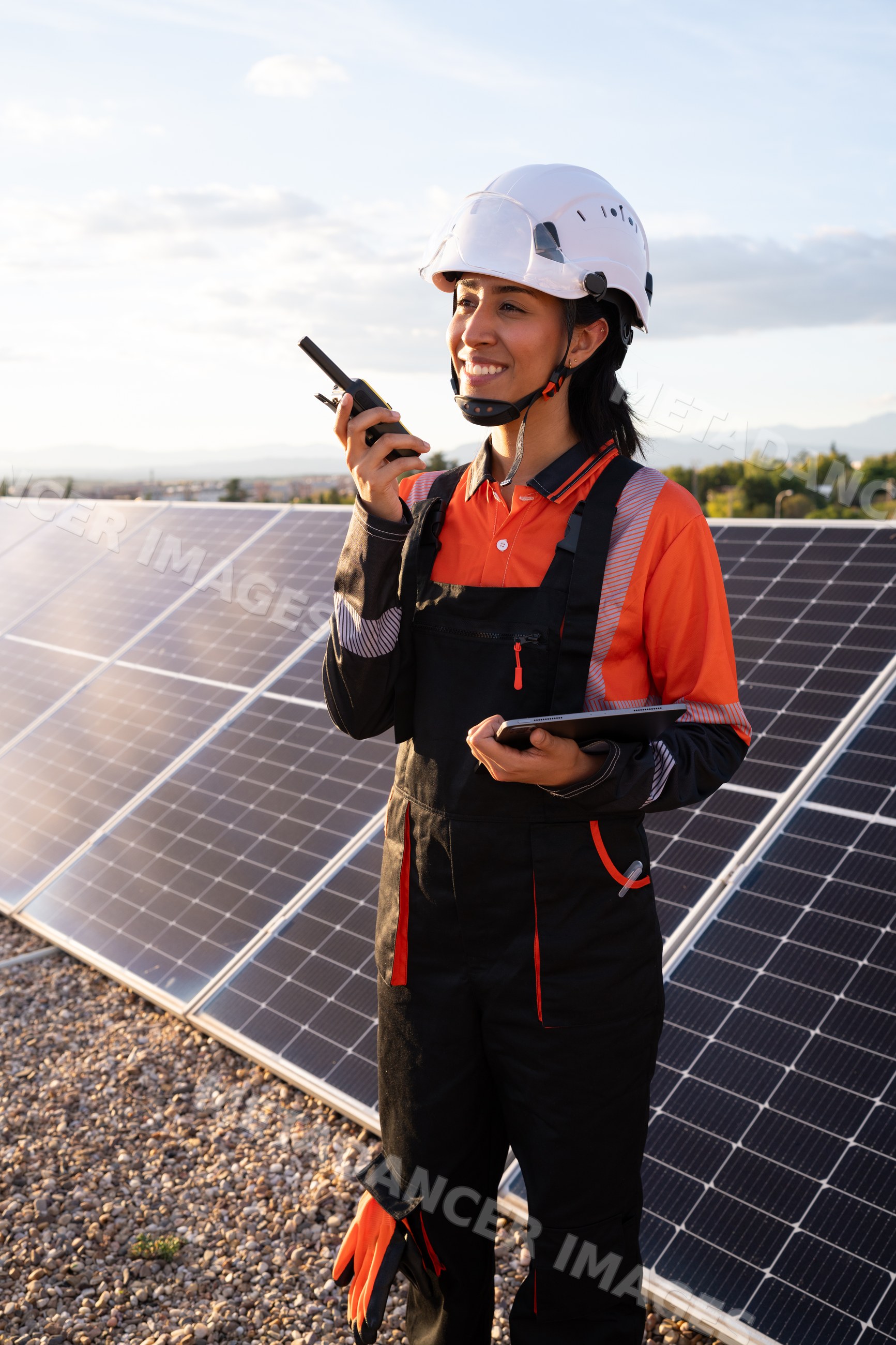 Female technician inspecting solar panels with walkie talkie outdoors