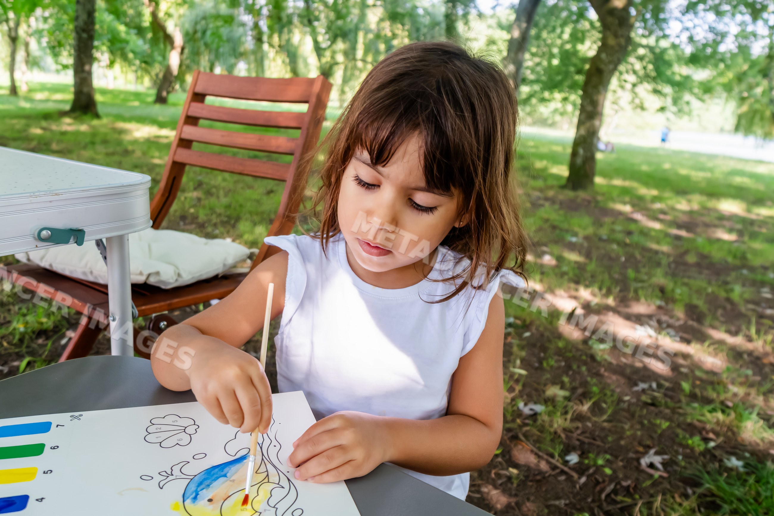 White child painting with watercolors outdoors in park setting