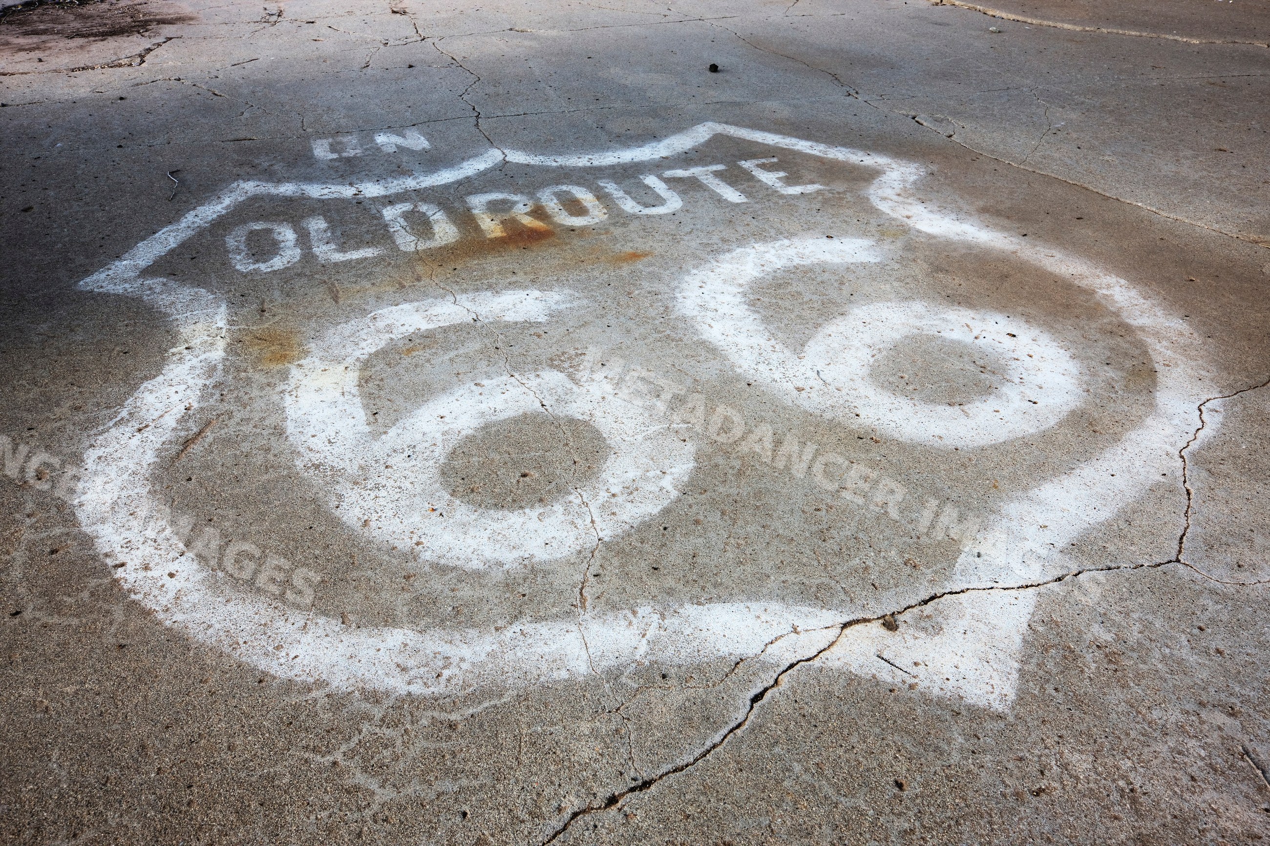 Old route 66 road shield painted on cracked asphalt