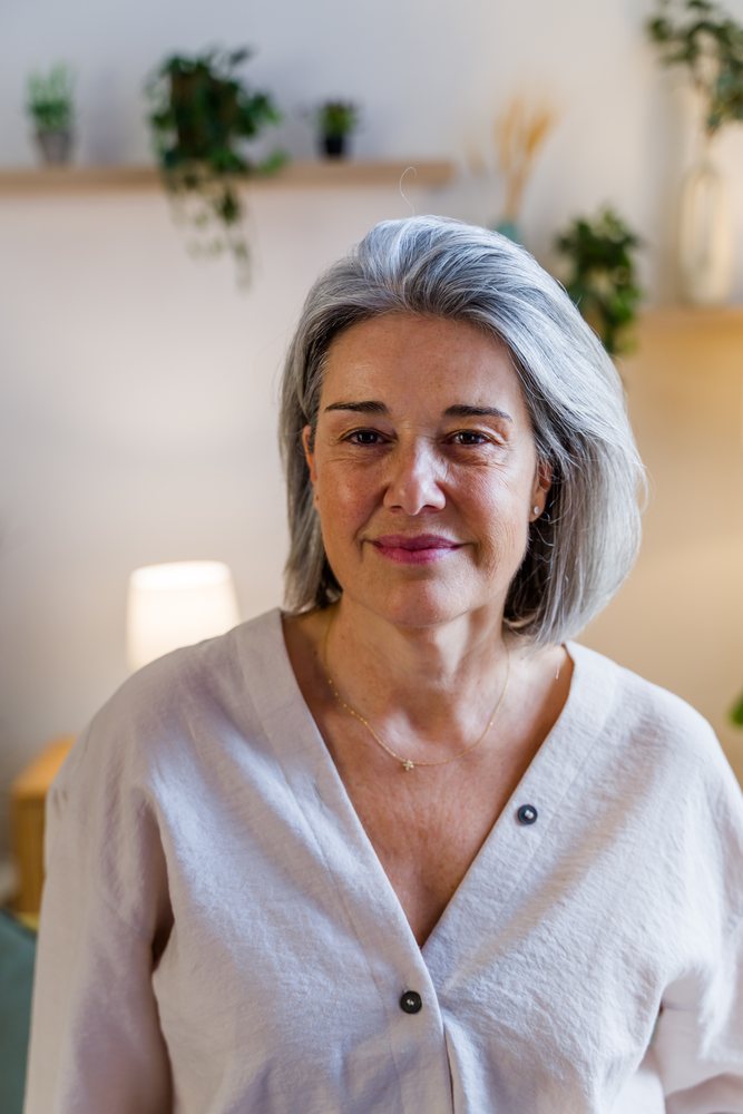 Middle-aged white woman with gray hair smiling indoors