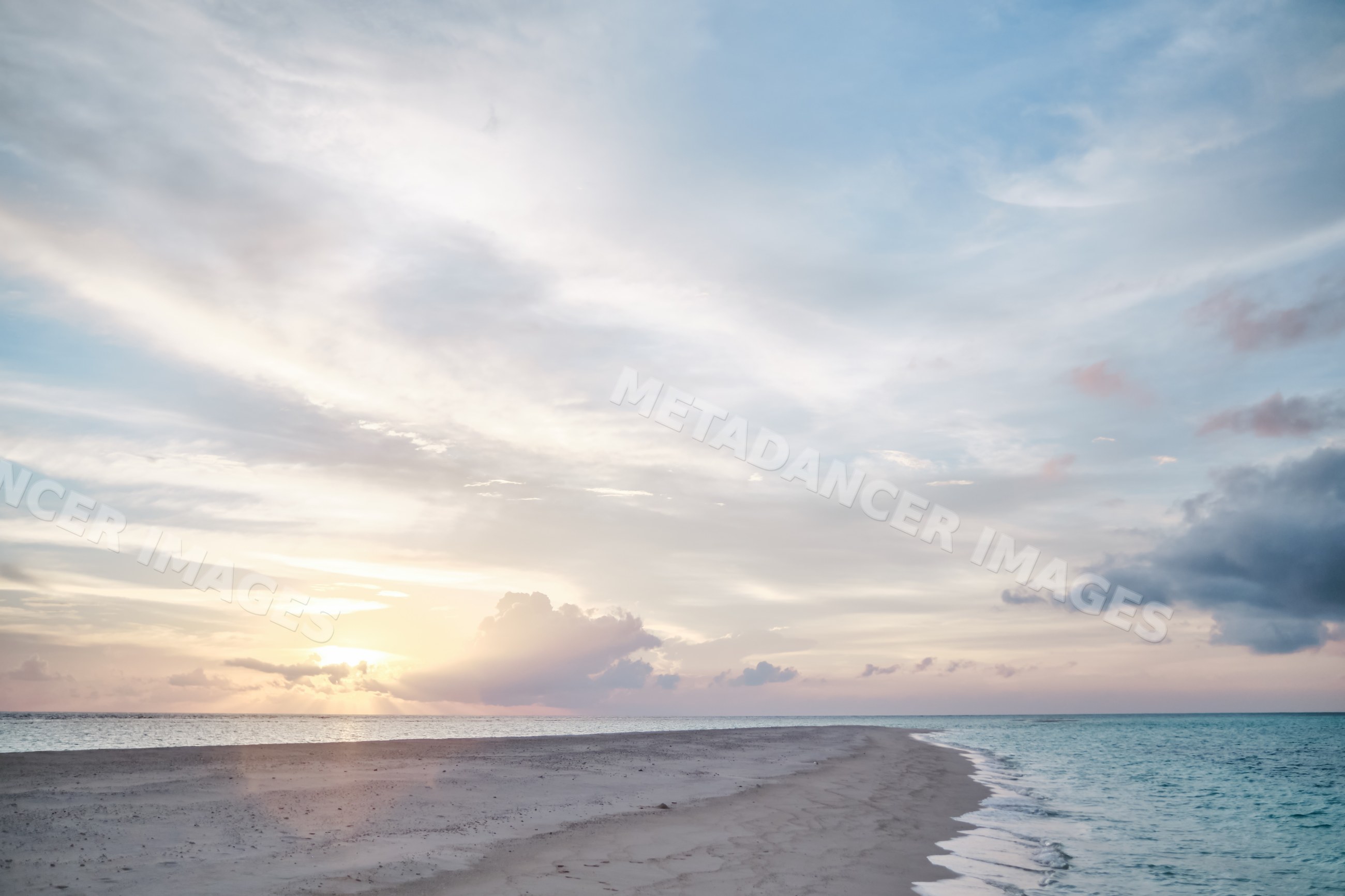 A tranquil sandbar stretches into the ocean at sunset in the Maldives