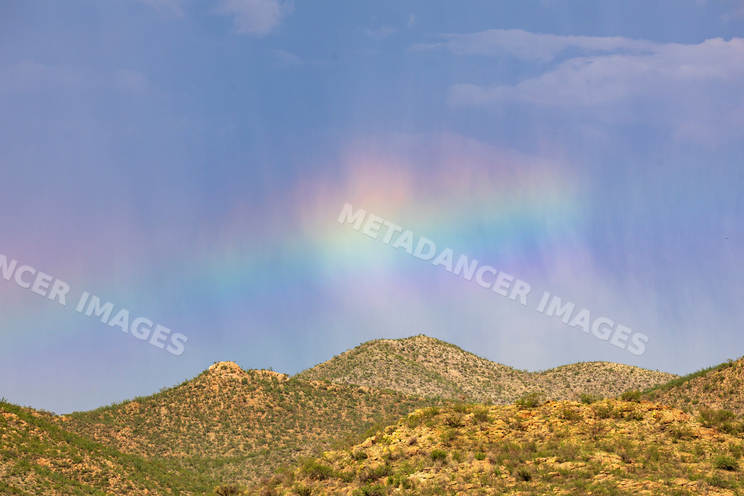 Rainbow over hills in mid-afternoon rainstorm in tombstone arizona