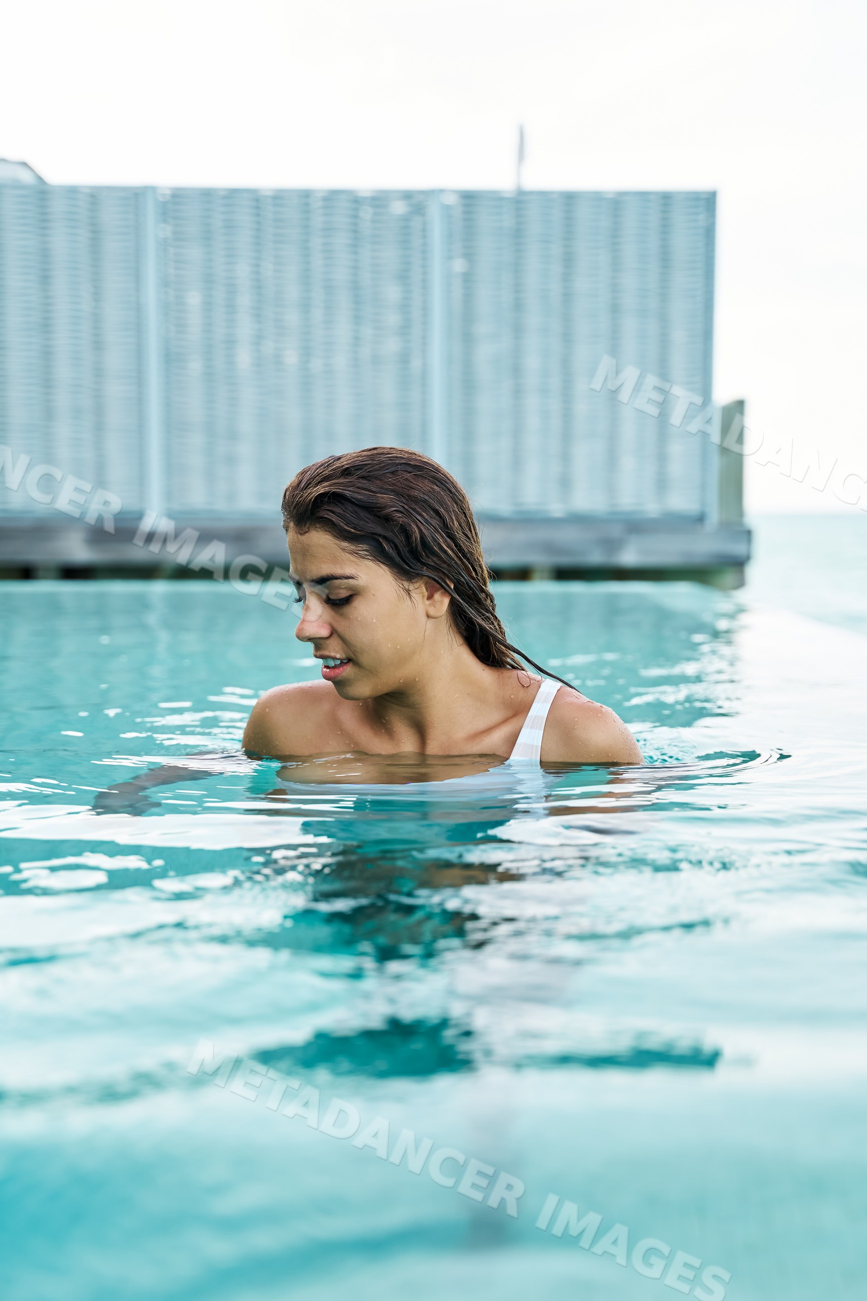 A white woman enjoys swimming and relaxing in a pool