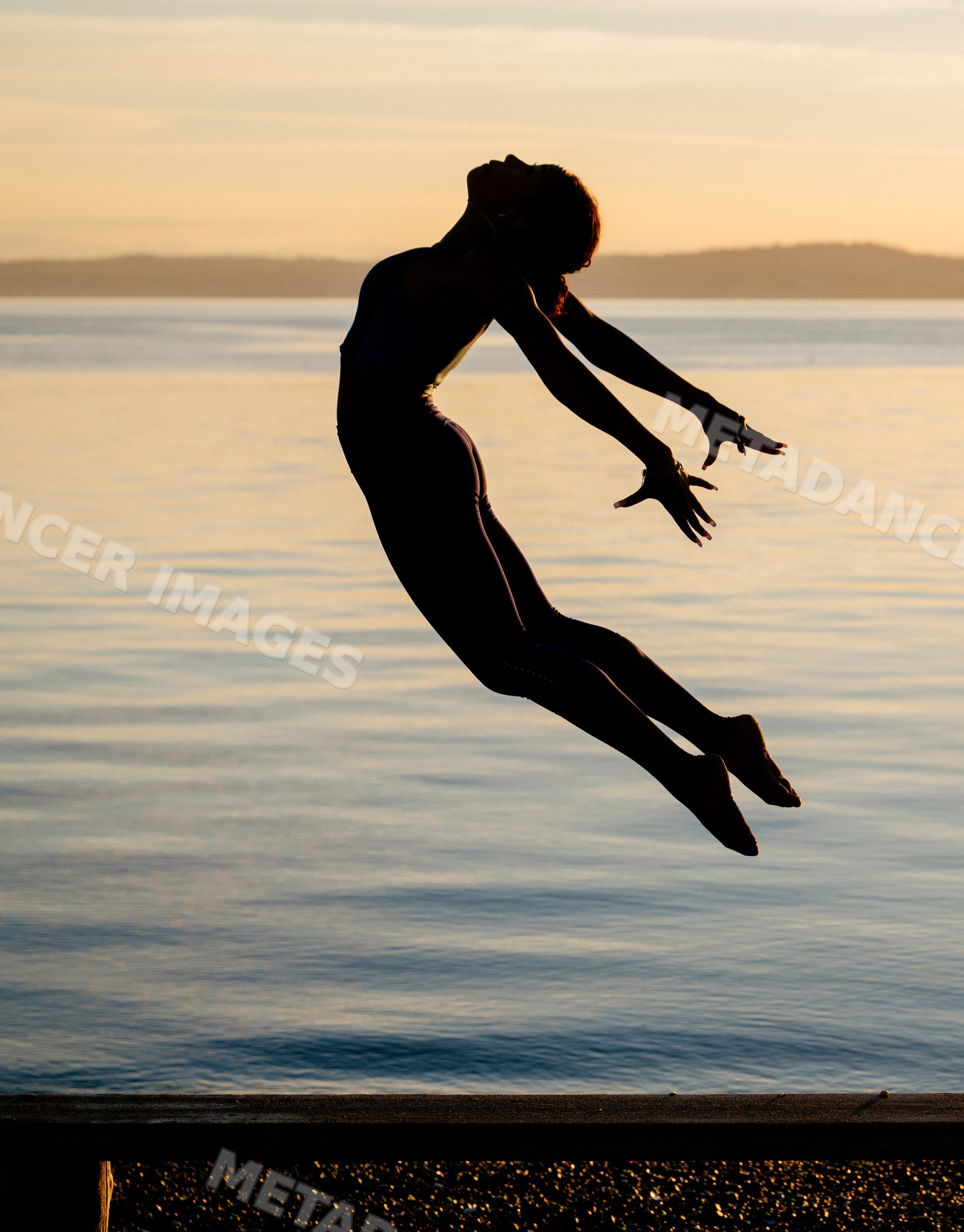 Hispanic woman jumping in yoga pose at lake during sunset