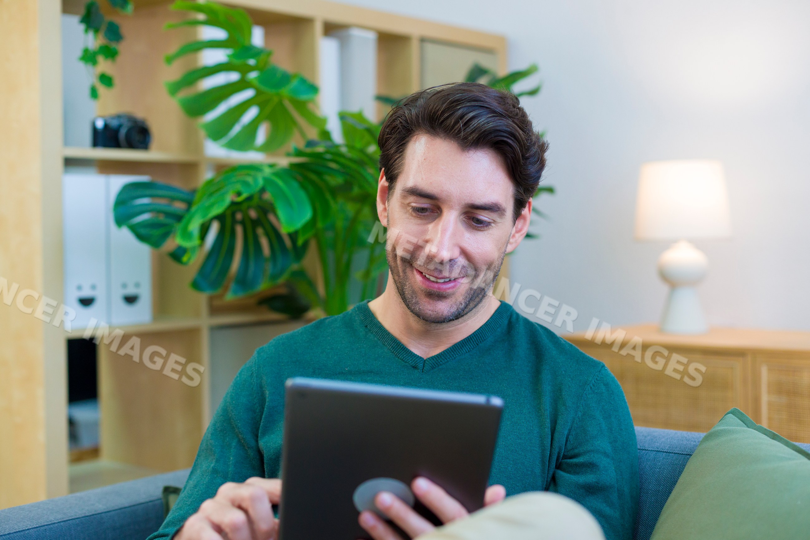 Young white man using tablet in modern living room