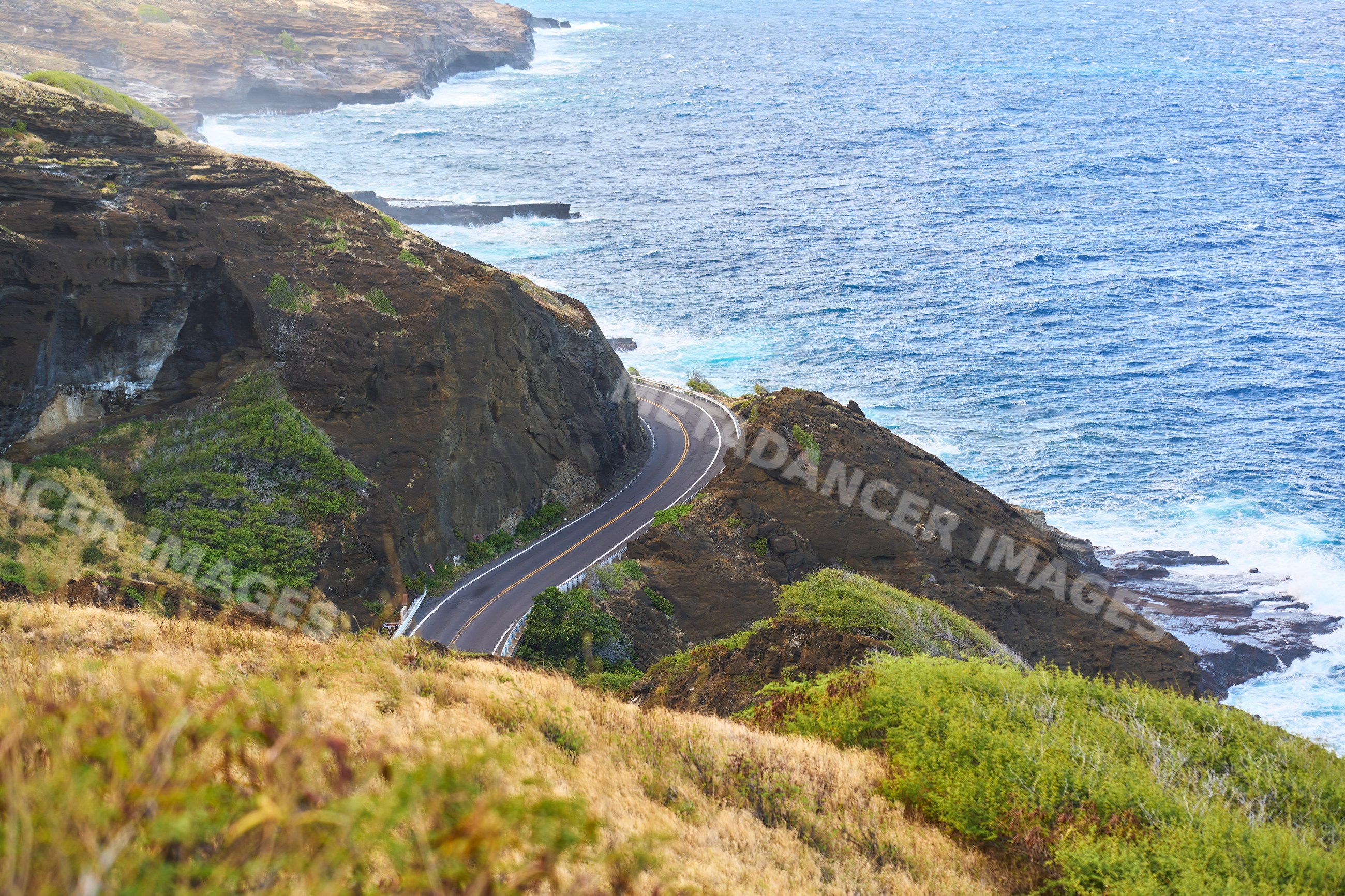 Coastal road winding around rocky cliffs by the ocean in Oahu Hawaii