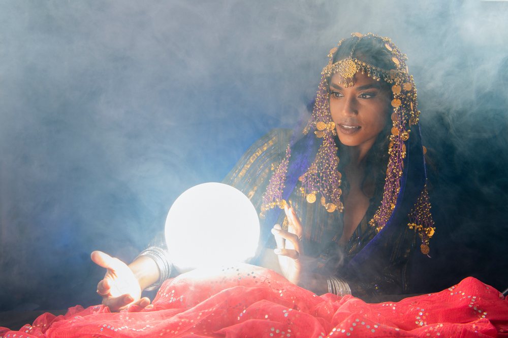 A fortune teller consults a glowing crystal ball surrounded by smoke