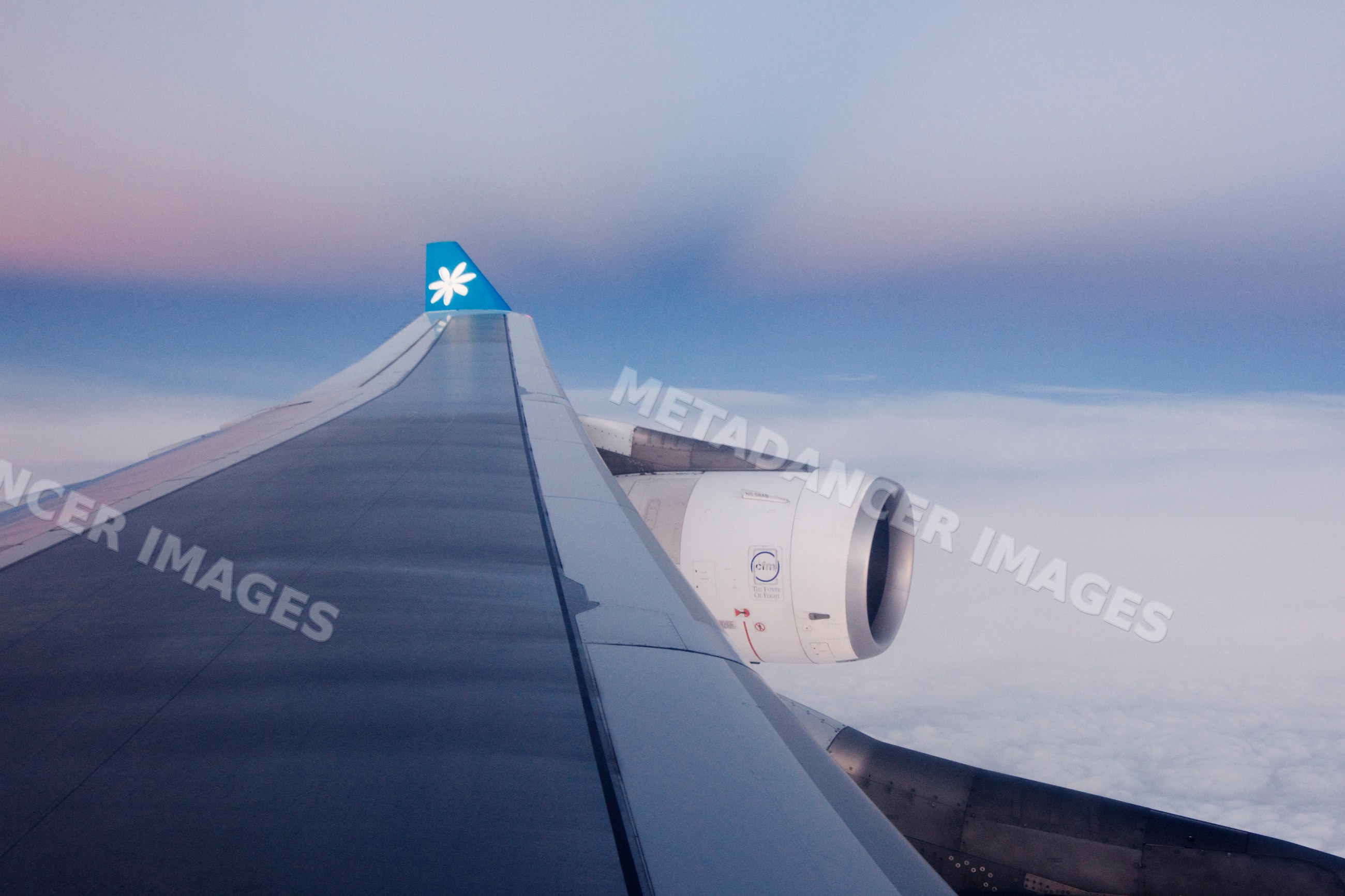 Airplane wing and engine in flight above clouds