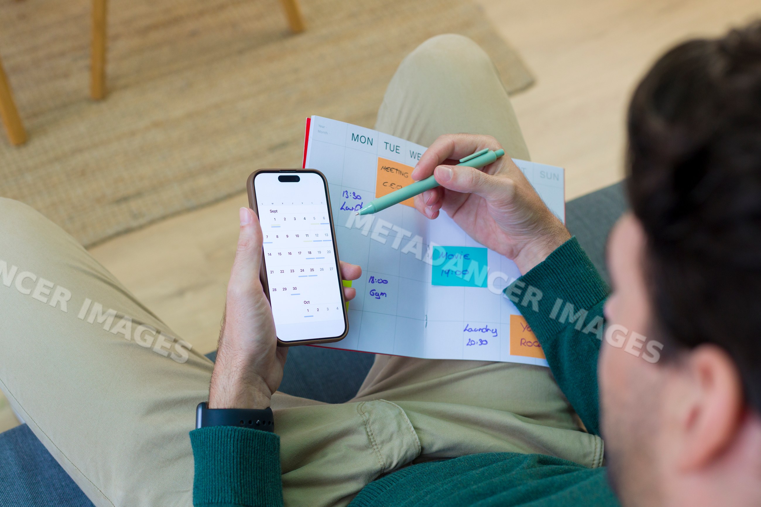 White person scheduling appointments in weekly planner with smartphone