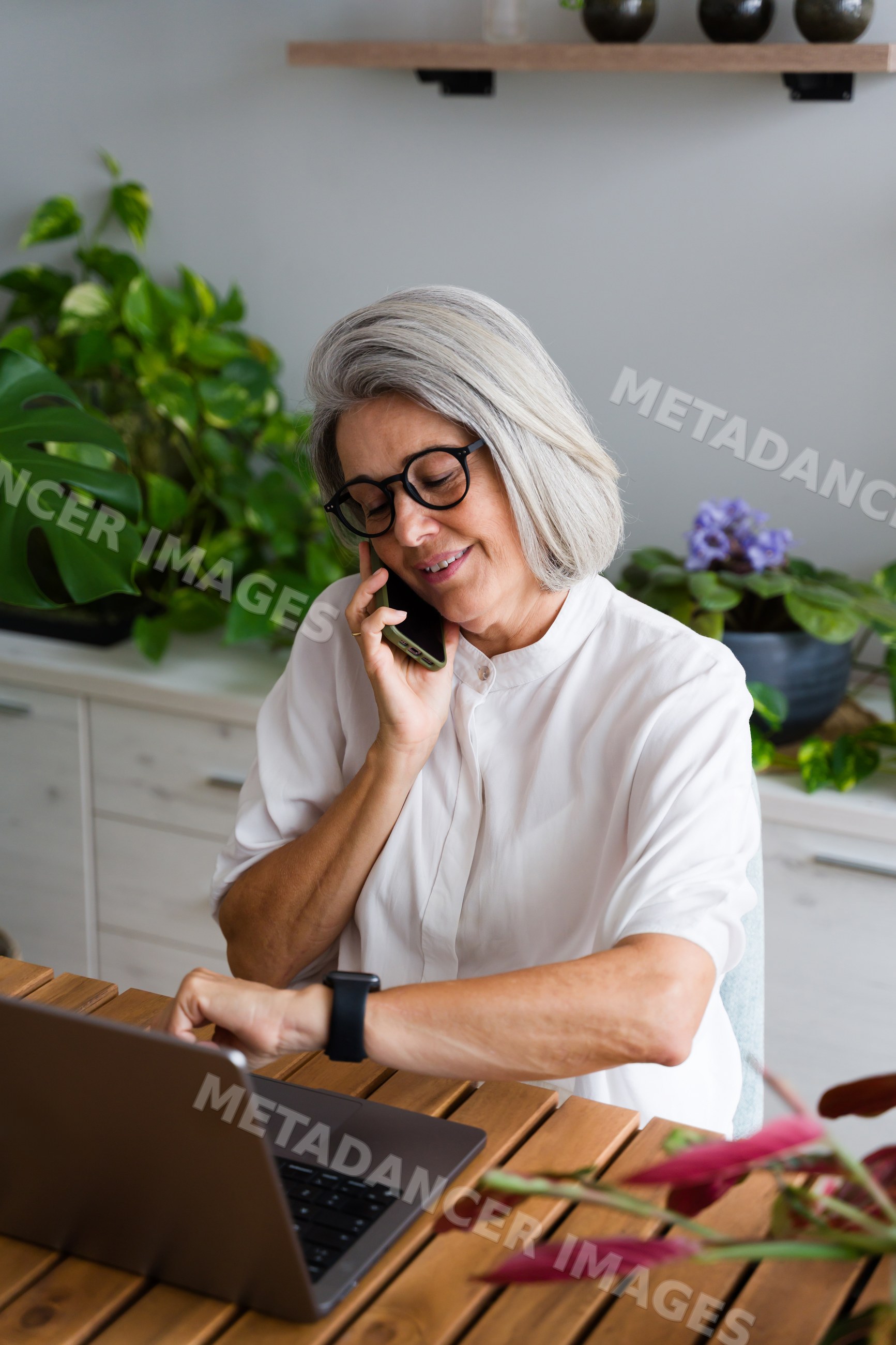 Mature white woman multitasking with phone and laptop