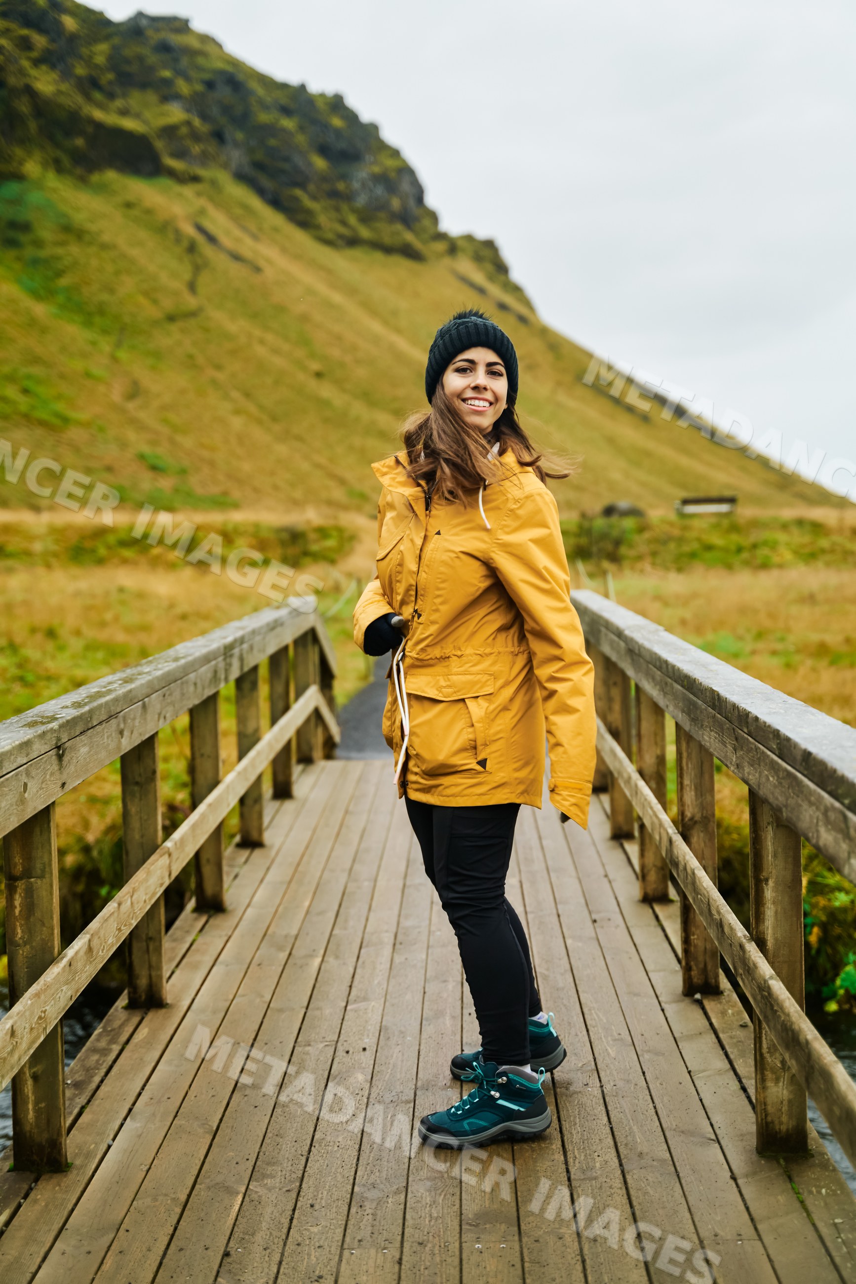 White Woman smiles on a wooden bridge while hiking outdoors