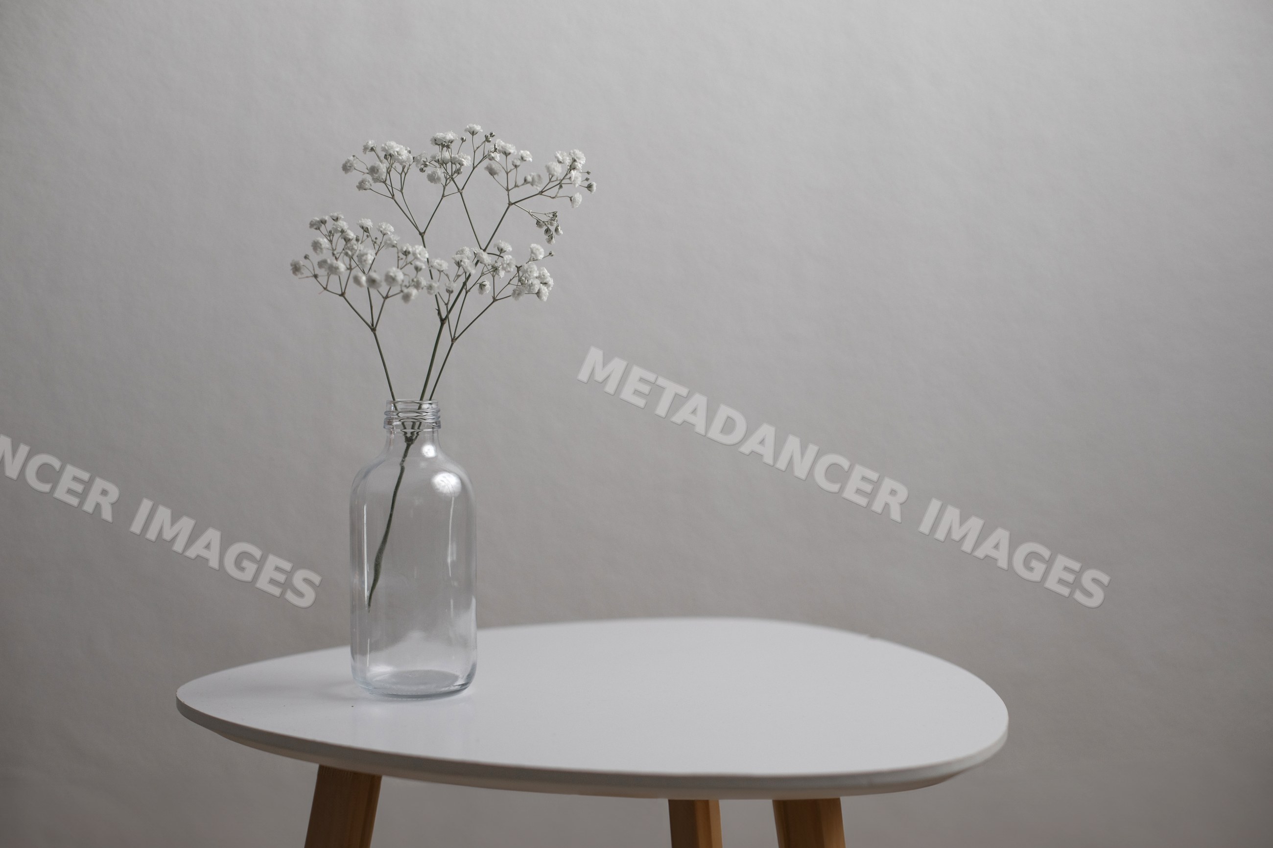 White flowers in glass bottle on modern minimalist table