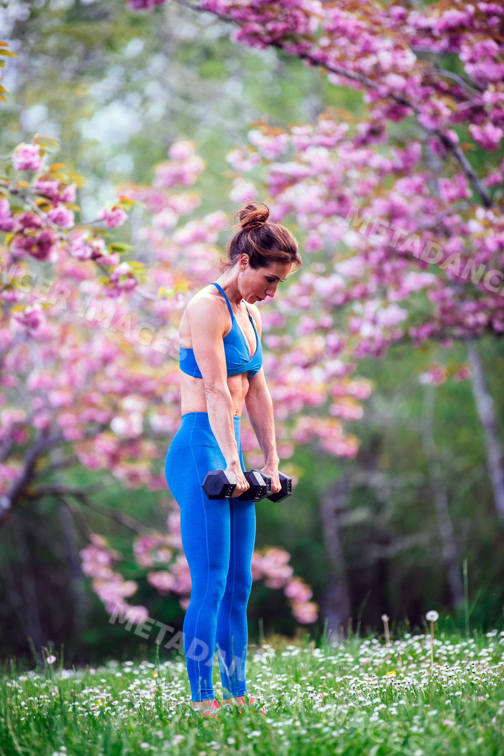 White woman exercising with dumbbells outdoors in spring bloom