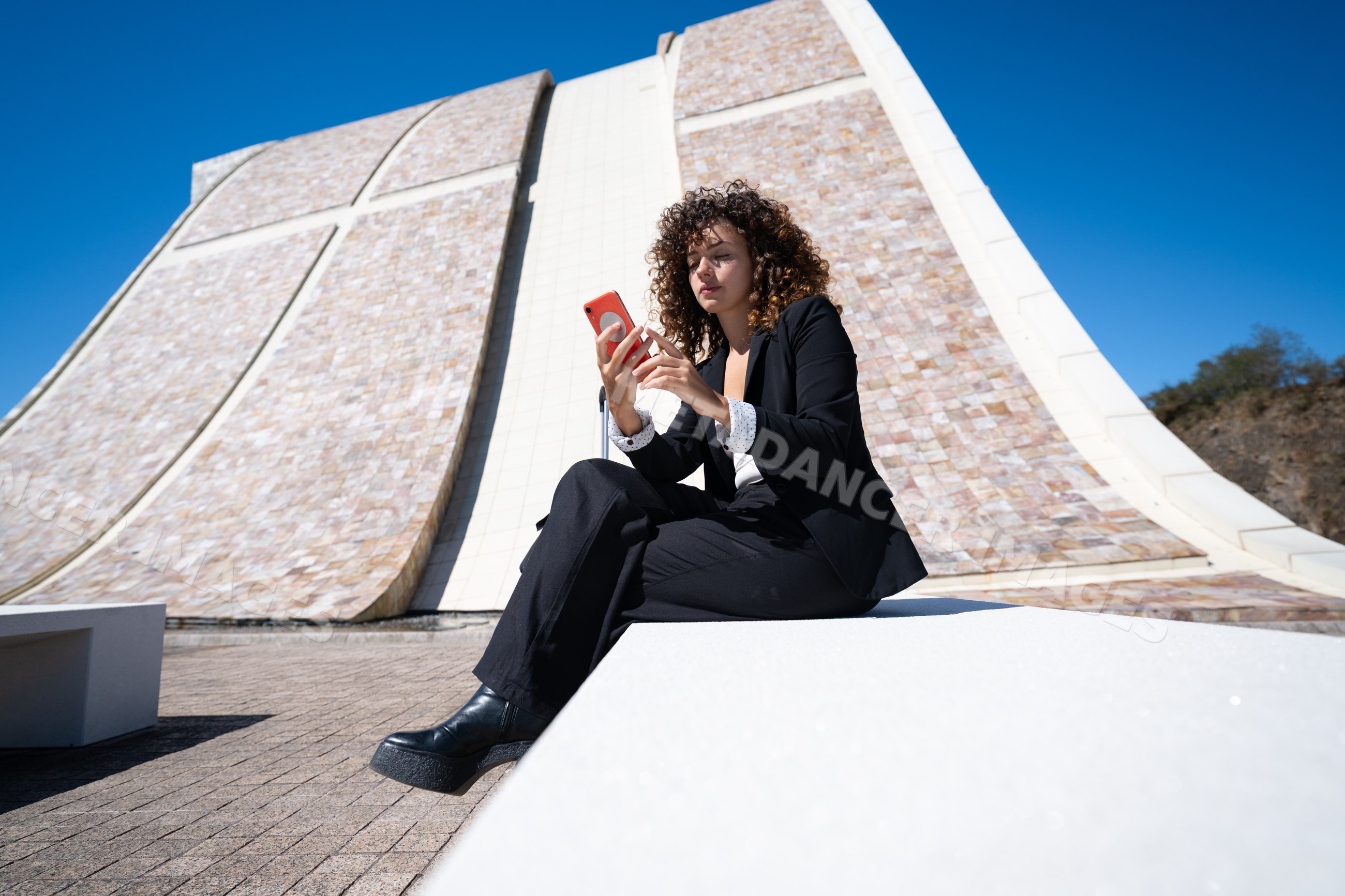Businesswoman sitting outdoors using smartphone