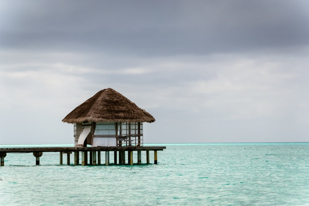 Overwater bungalow on a wooden pier over turquoise ocean