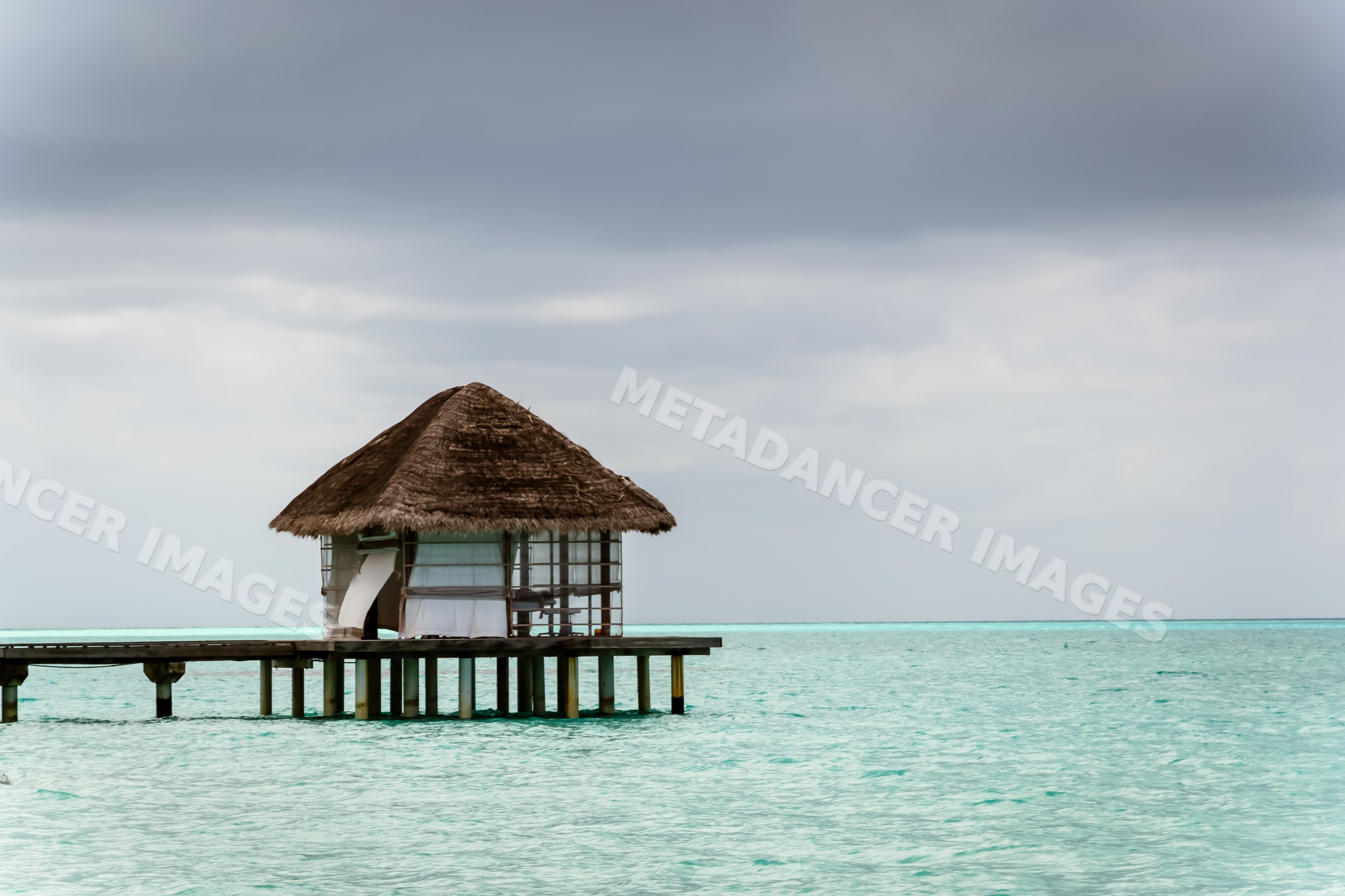 Overwater bungalow on a wooden pier over turquoise ocean
