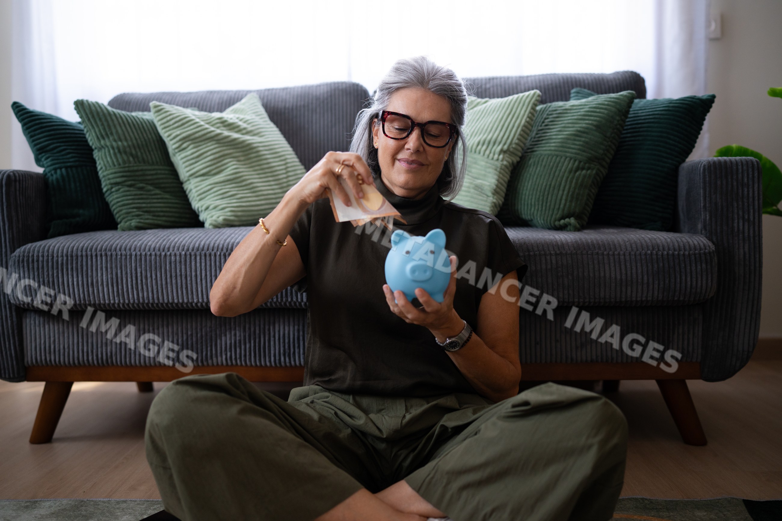 White woman placing banknotes into blue piggy bank