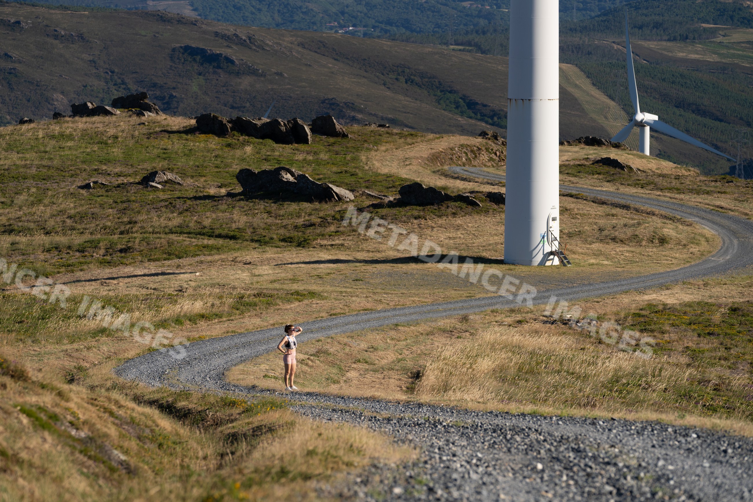 A white woman stands on a gravel path looking