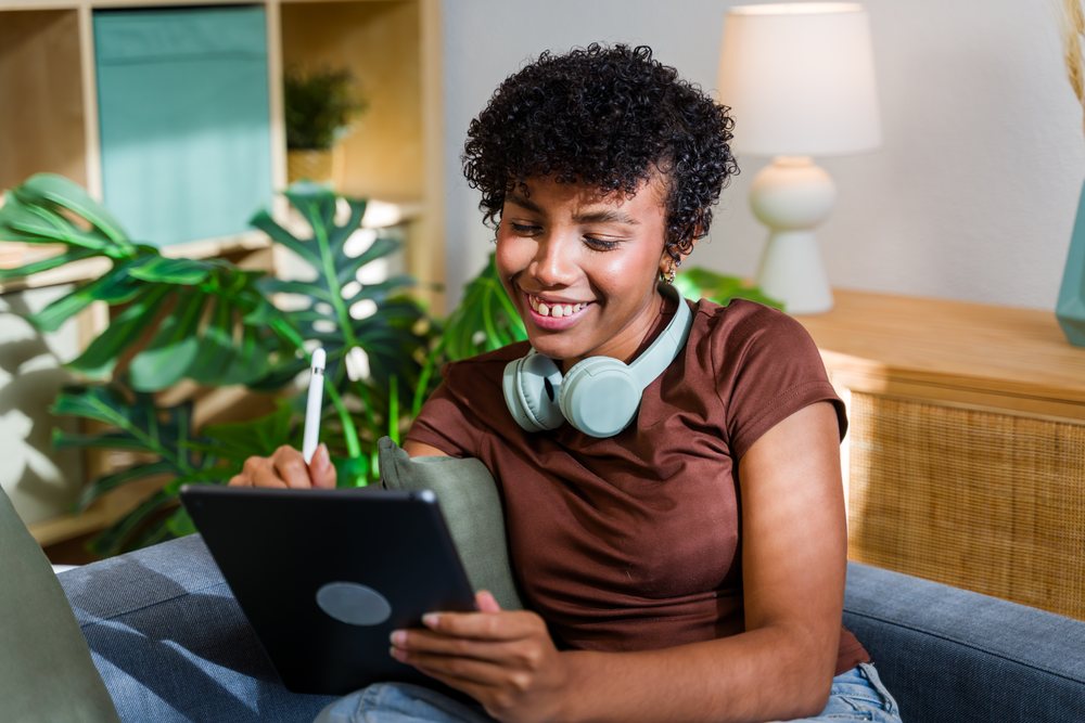 African American woman using tablet with stylus and headphones