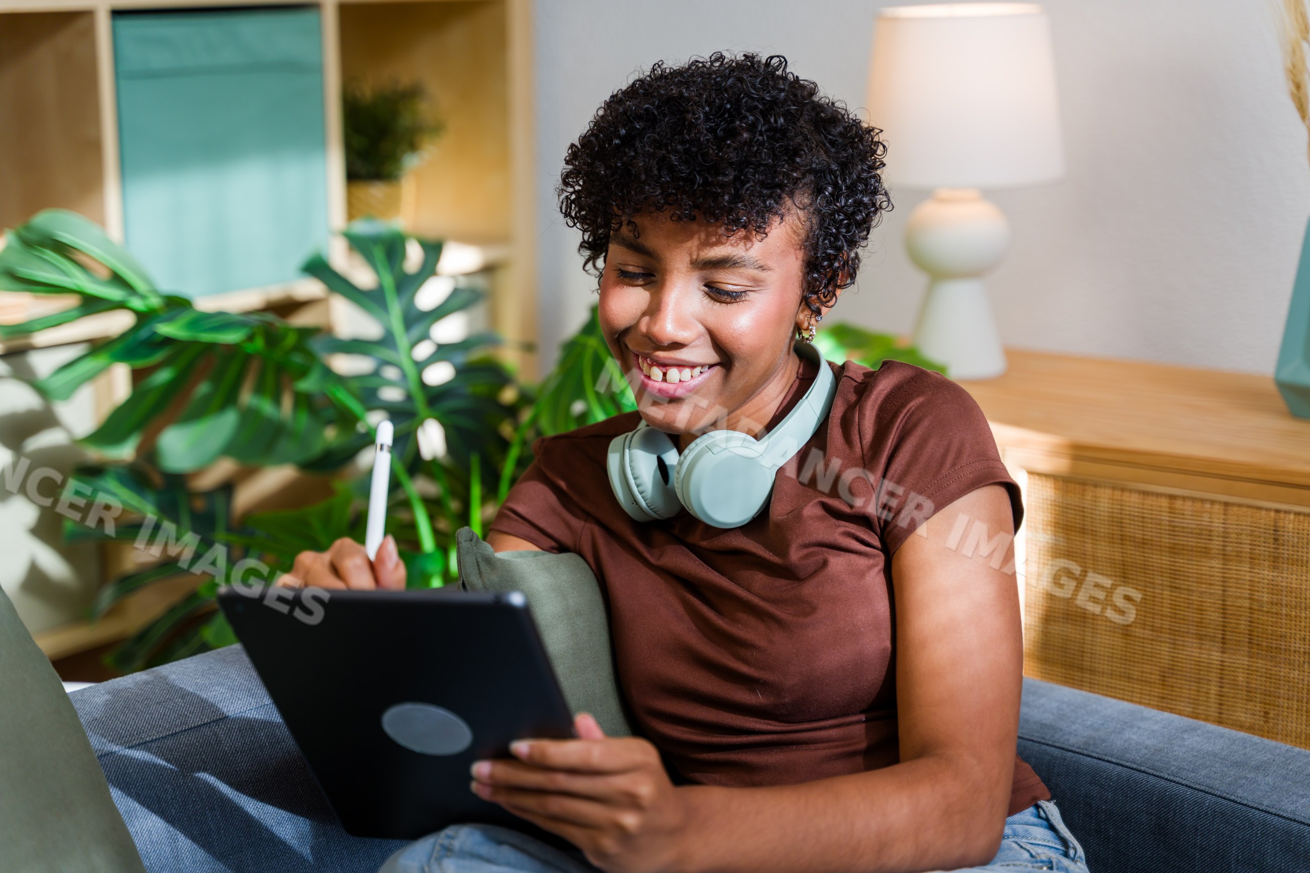 African American woman using tablet with stylus and headphones