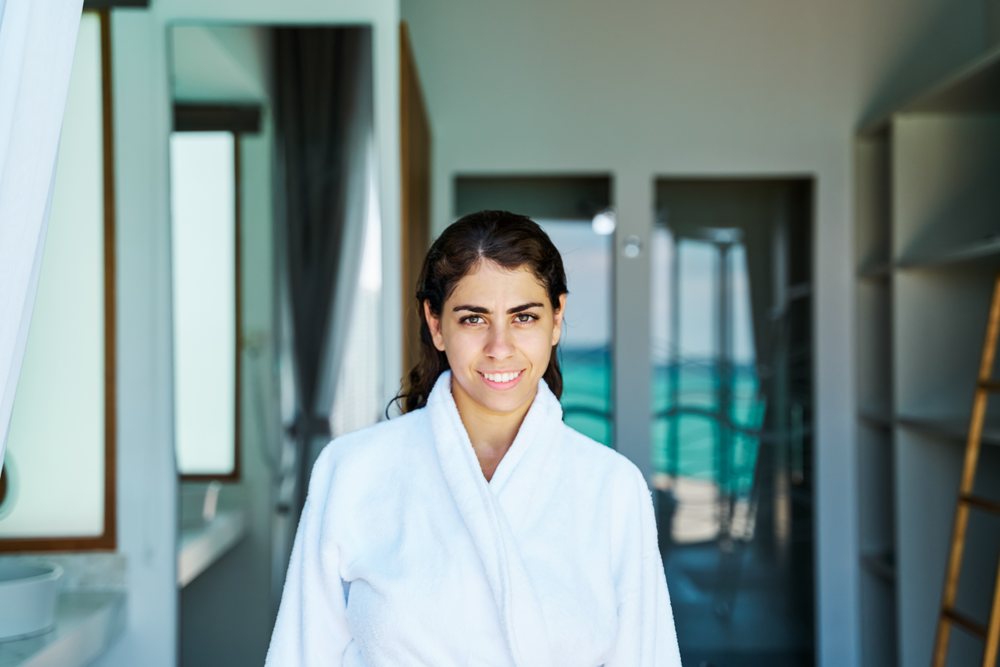 A white woman smiles inside a stylish hotel room in a hotel