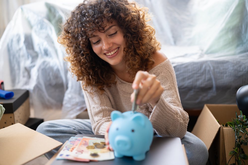 White woman saving money in piggy bank during move at home