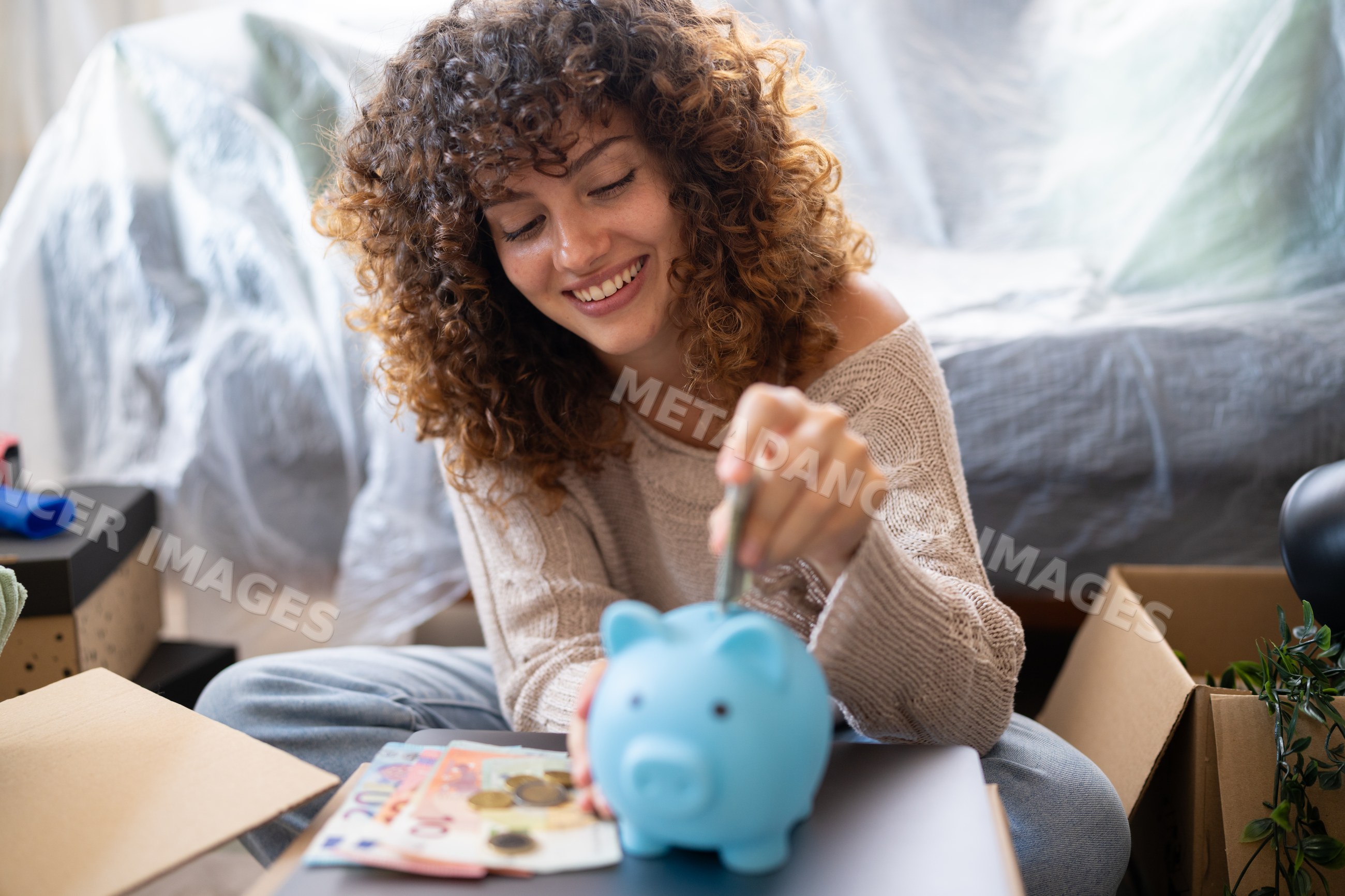 White woman saving money in piggy bank during move at home