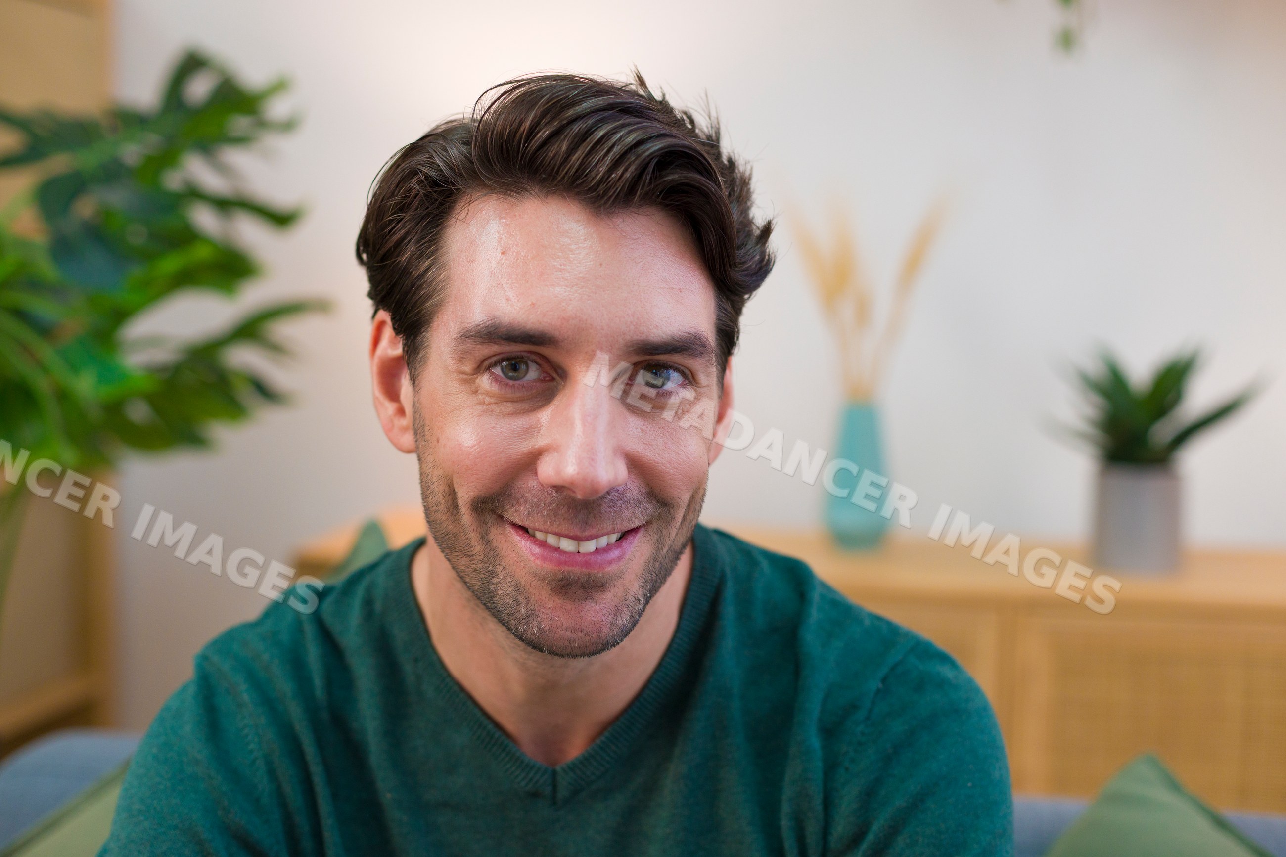 Smiling young white adult man sitting indoors