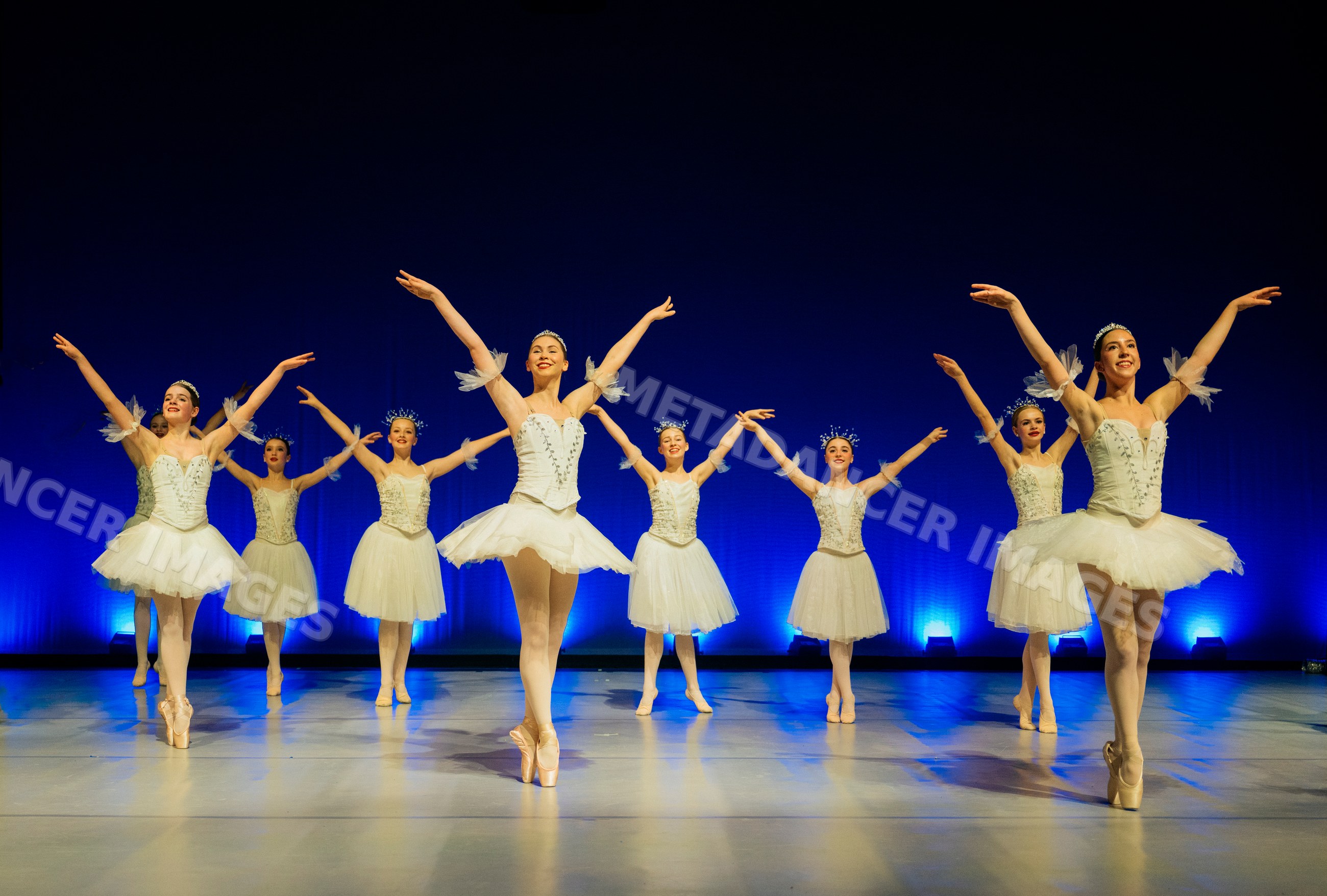 Female ballet dancers perform a graceful group dance on stage