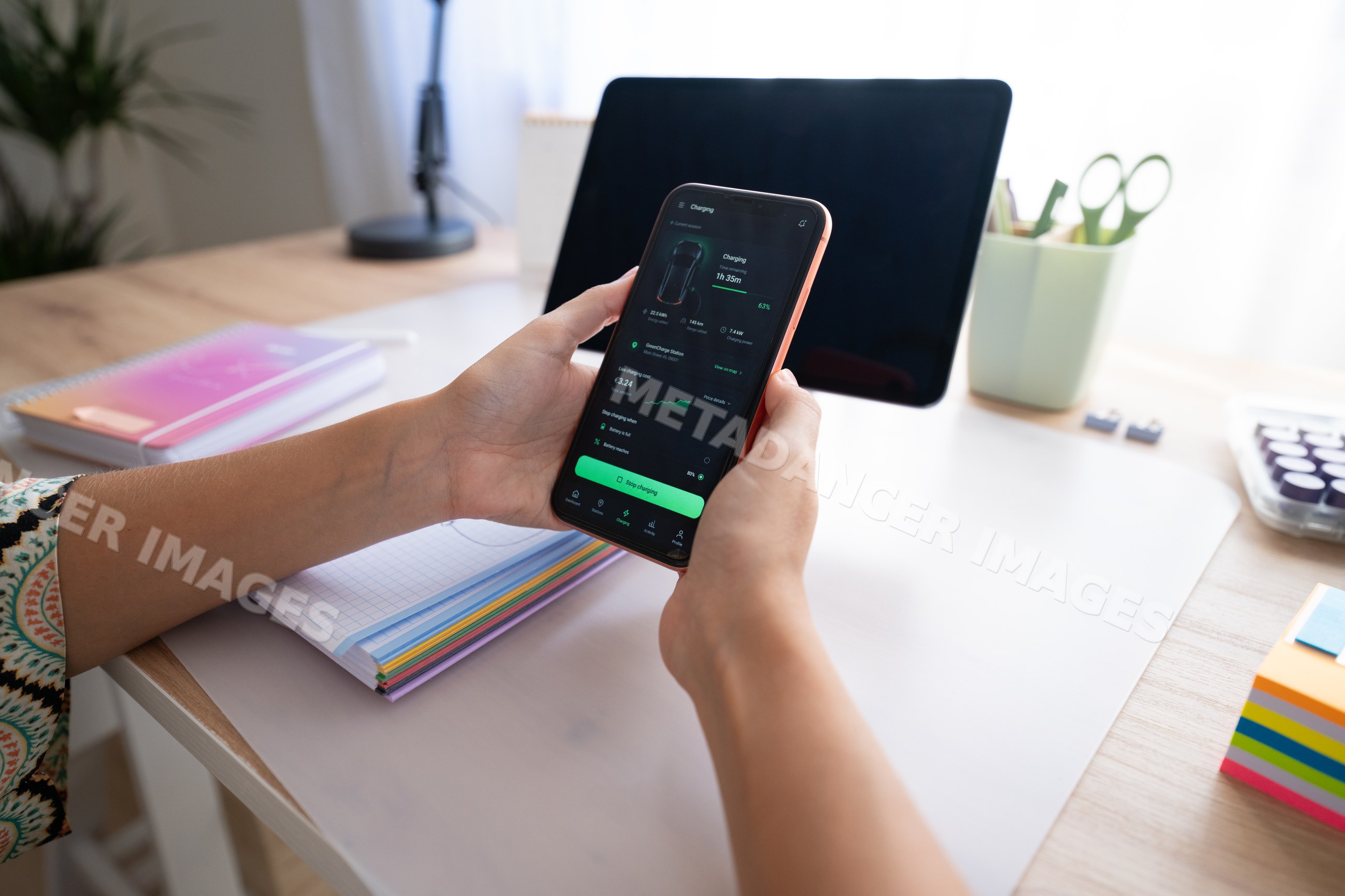 Smartphone displaying charging app held over organized desk