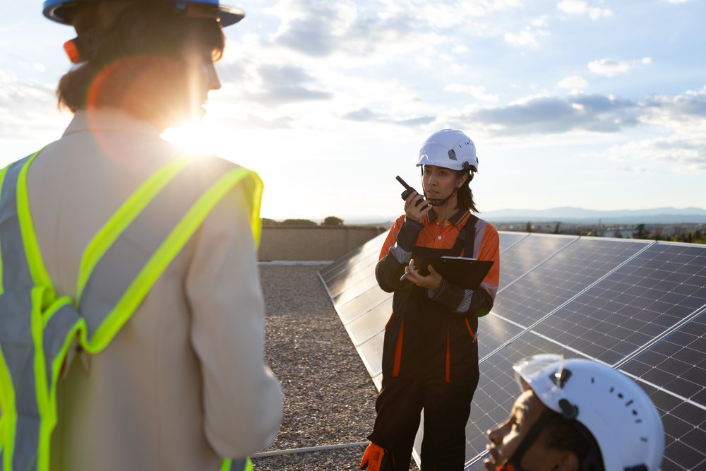 Technician communicating by solar panels at outdoor rooftop work site
