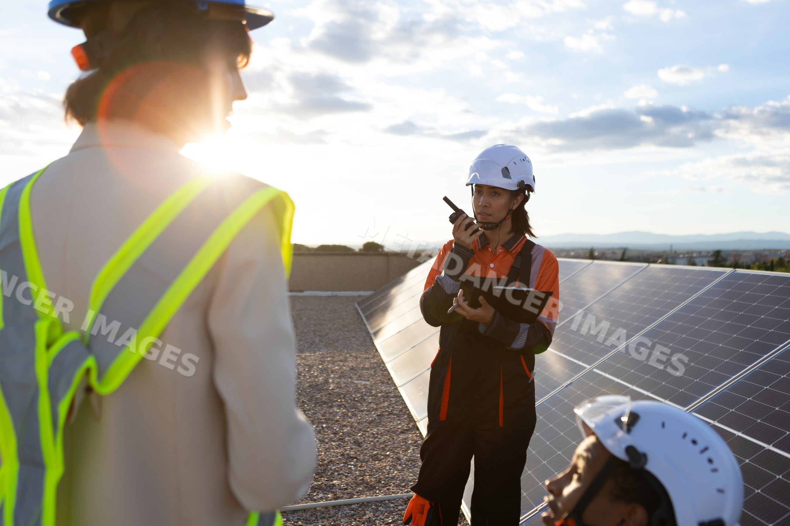 Technician communicating by solar panels at outdoor rooftop work site