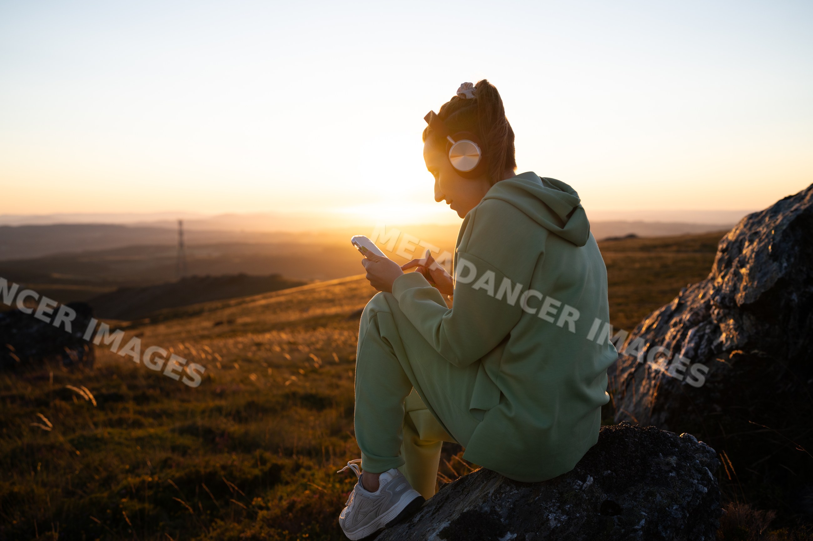 Young white woman listening to music on smartphone outdoors
