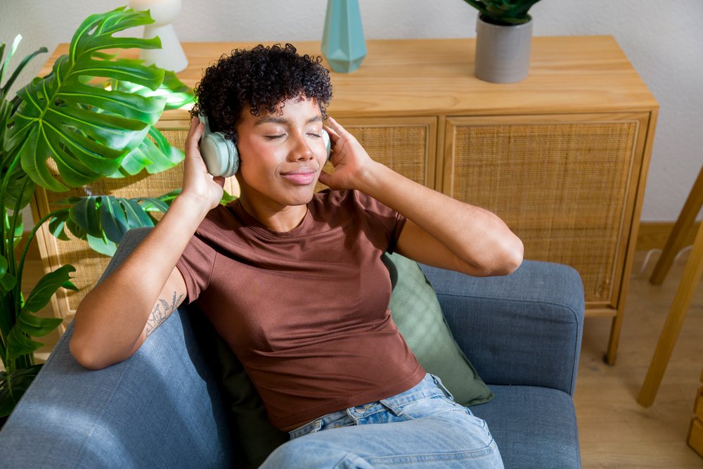 African American woman relaxing on couch listening to music