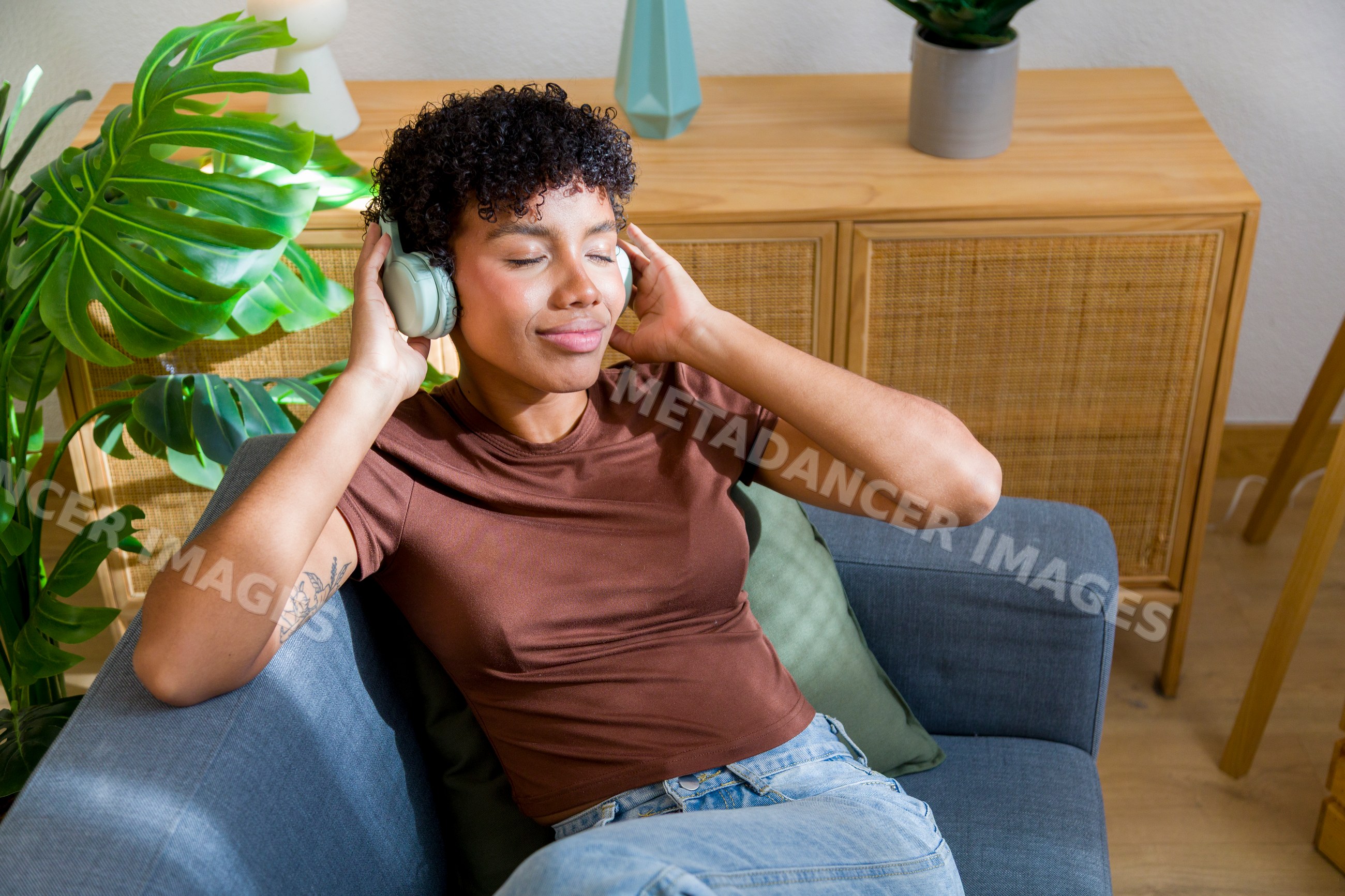 African American woman relaxing on couch listening to music