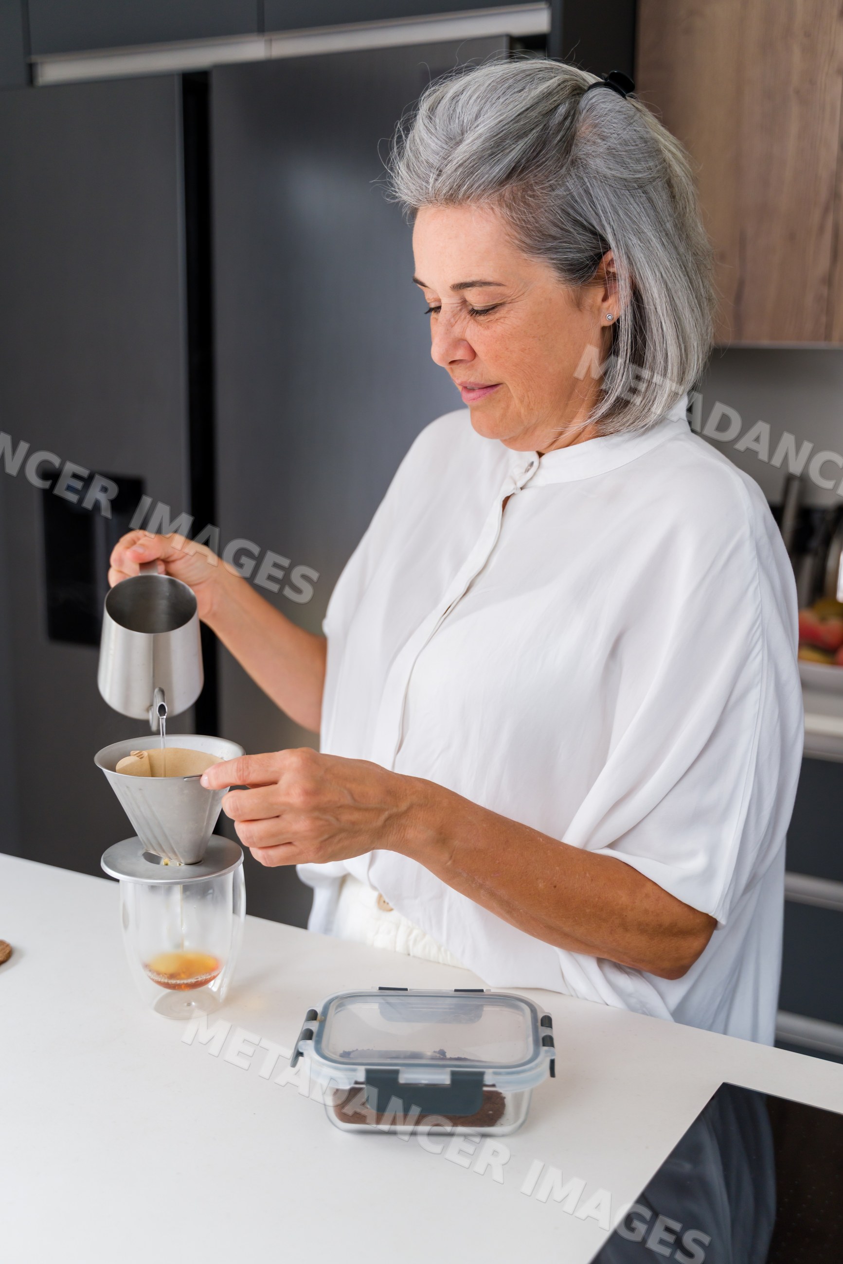 White Woman making pour over coffee in modern home kitchen