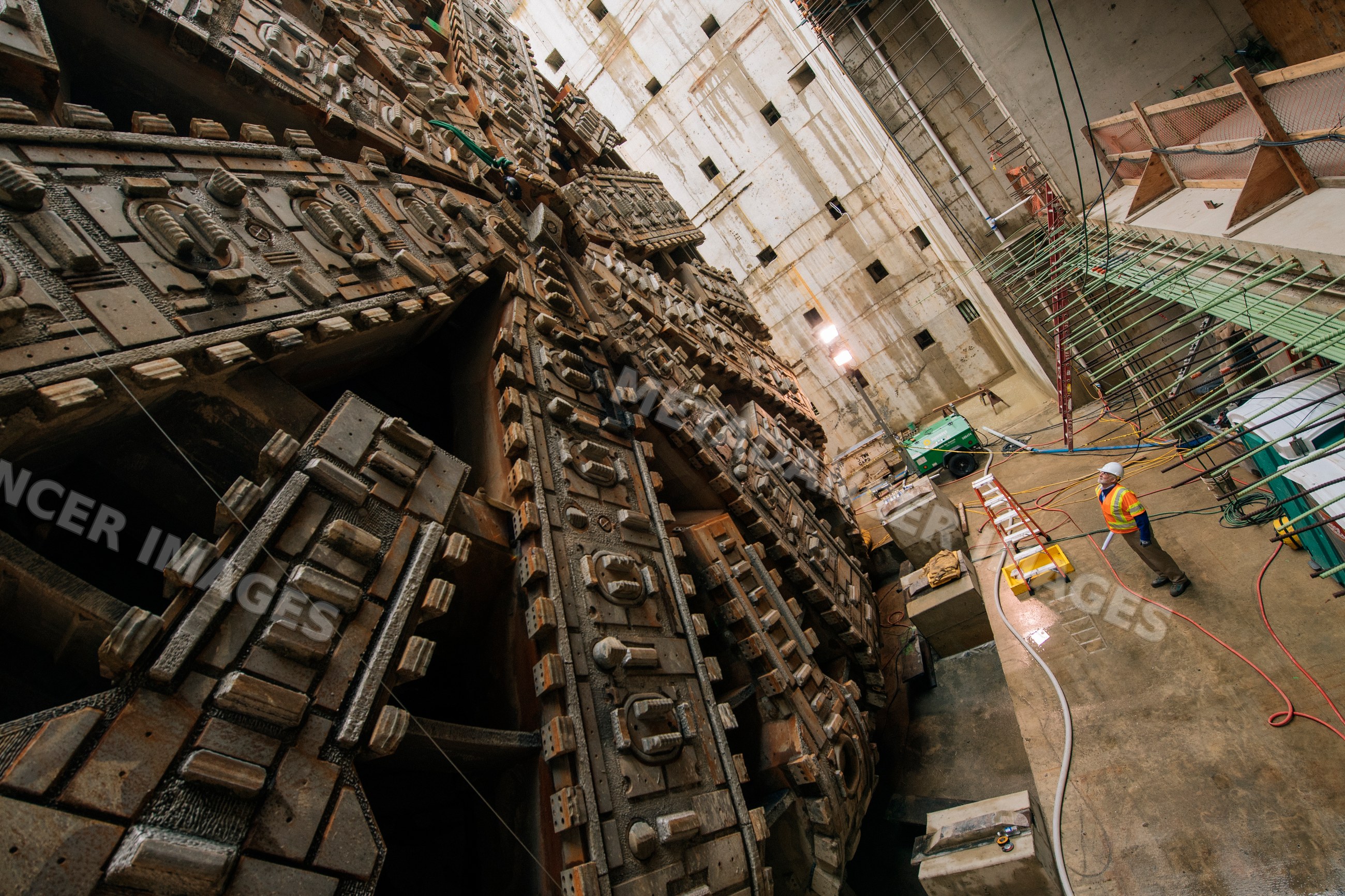 Two construction white workers inspect a tunnel boring machine