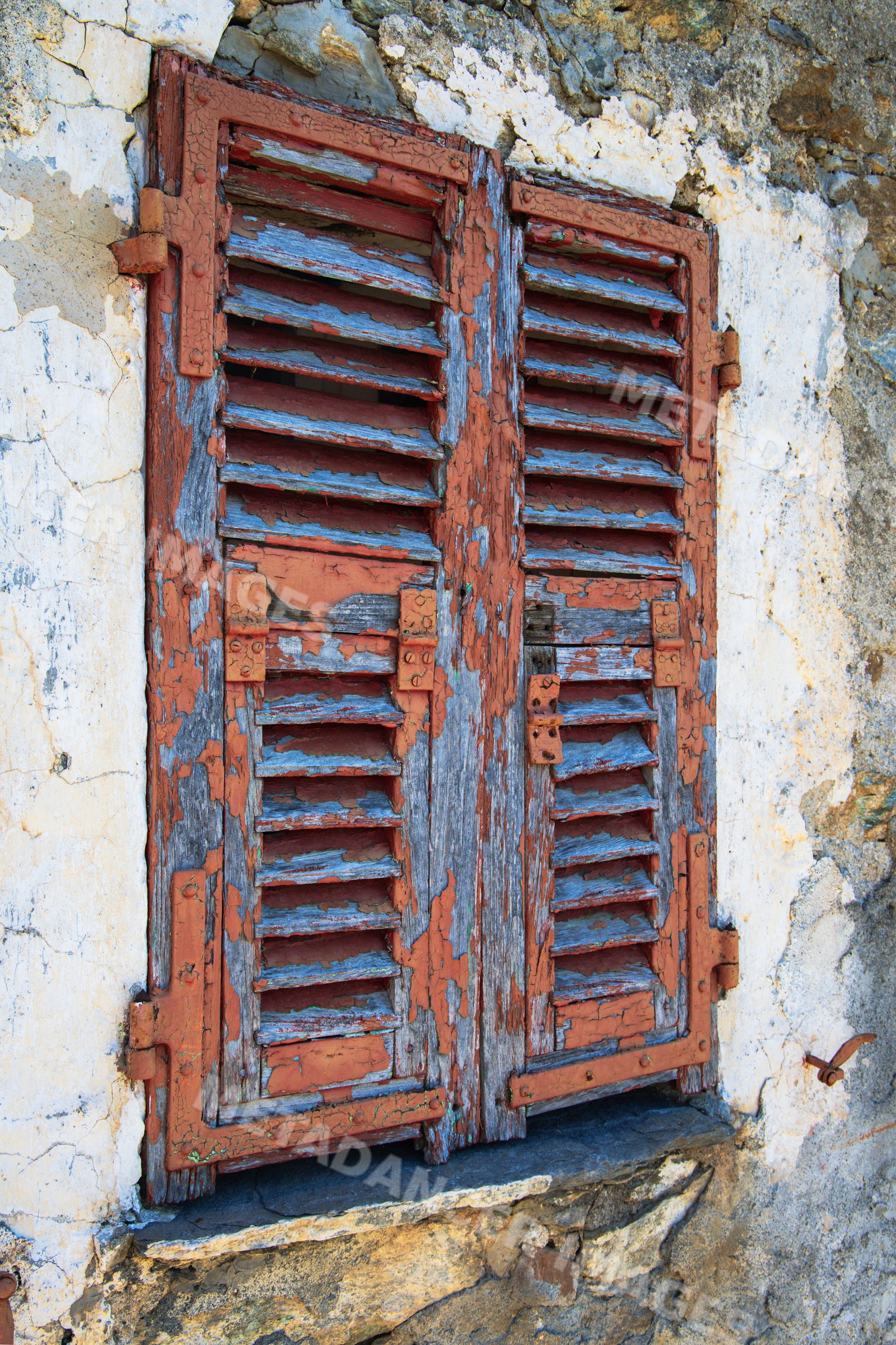 Weathered wooden window shutters on stone wall