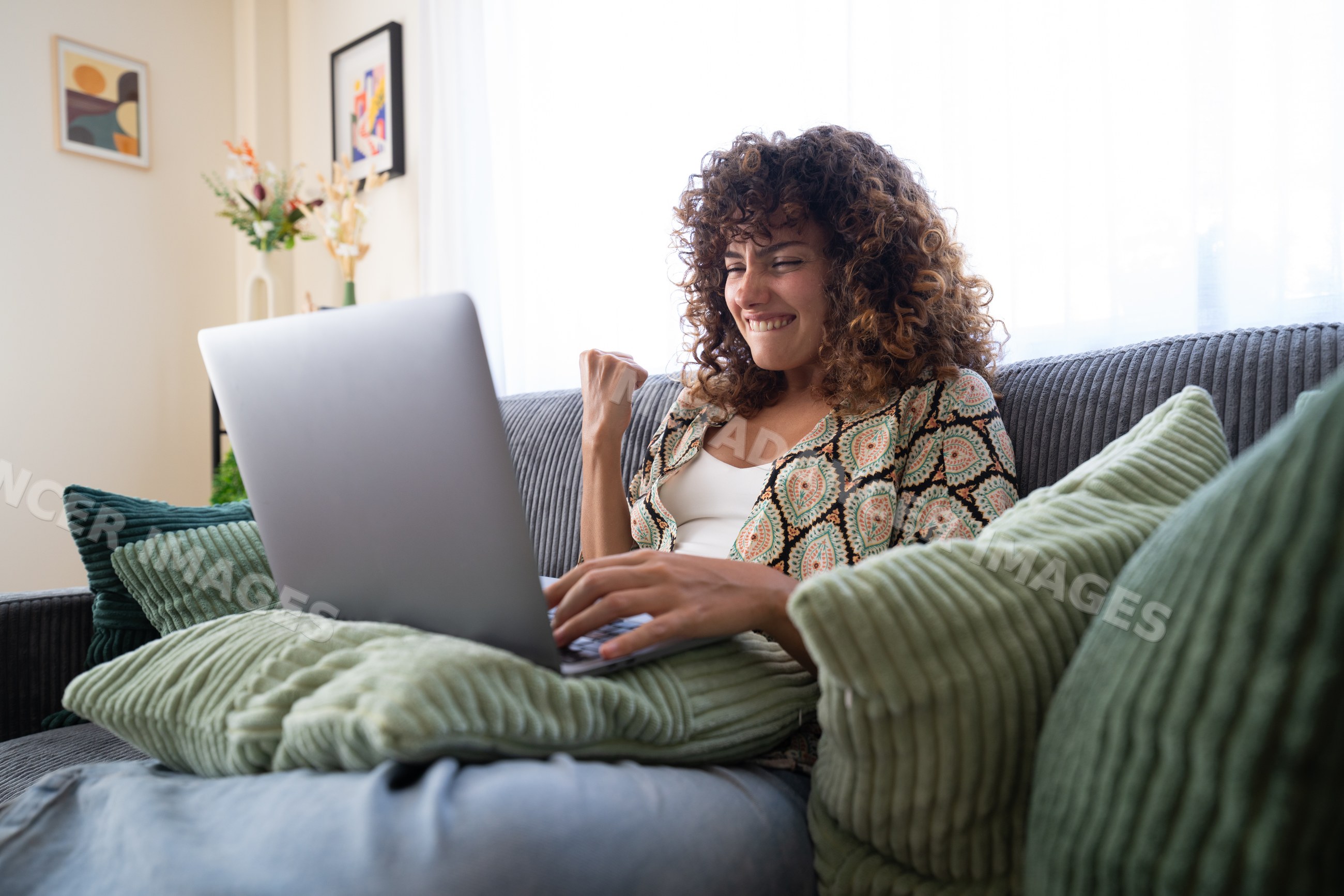 White woman cheering on a couch using laptop