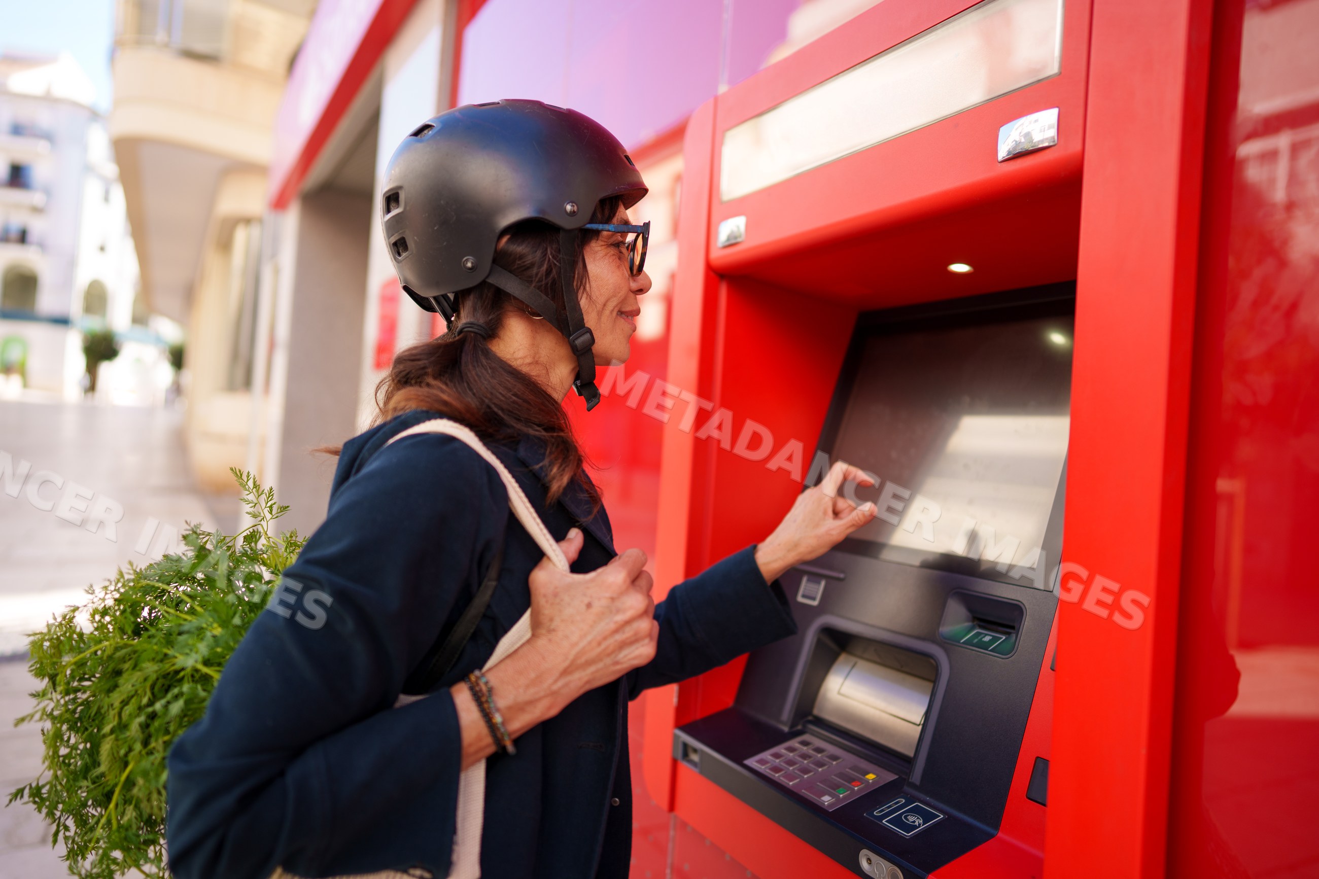 Hispanic woman using red atm outdoors
