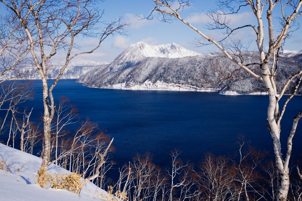 Lake mashu with snow and birch trees, japan
